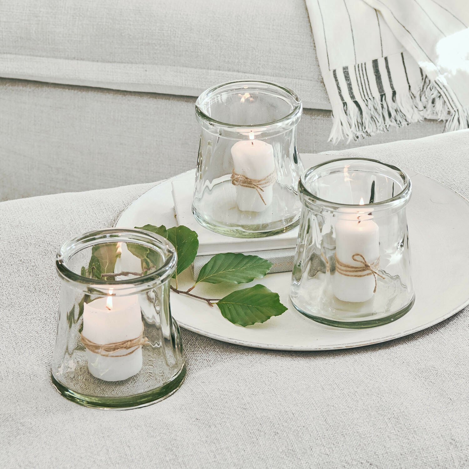 Lot de 3 photophores Gravière Ensemble de trois photophores en verre avec bougies blanches et corde naturelle sur fond clair