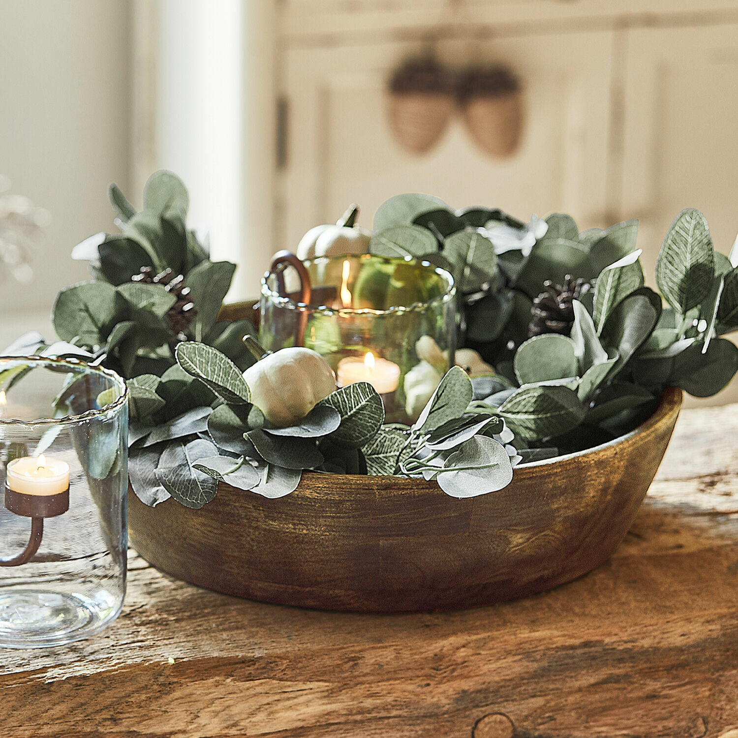 Coupe Crisfield Bol en bois décoratif avec feuillage vert et bougies dans des photophores en verre sur une table