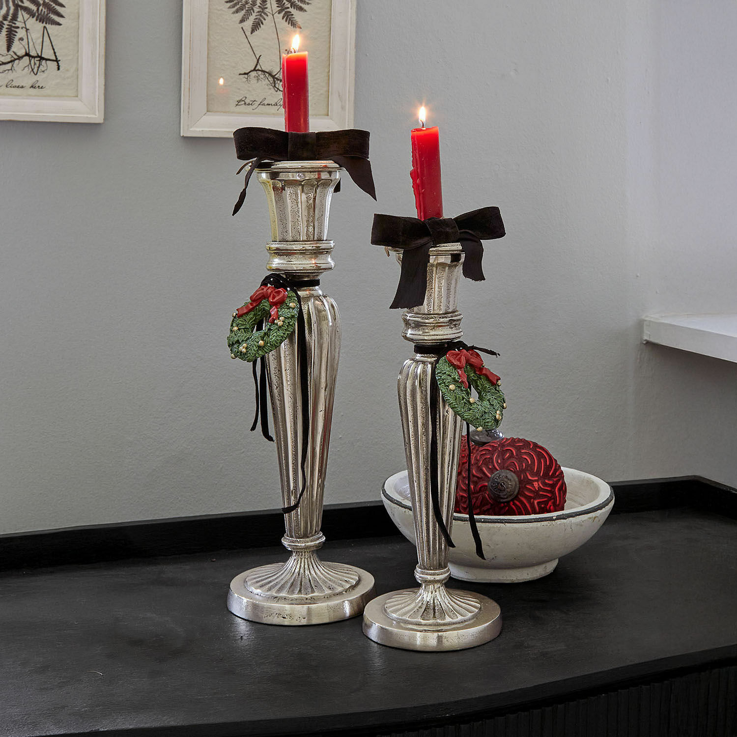 Lot de 2 bougeoirs Zahfira Deux chandeliers argentés avec bougies rouges et décorations de couronne verte sur surface noire
