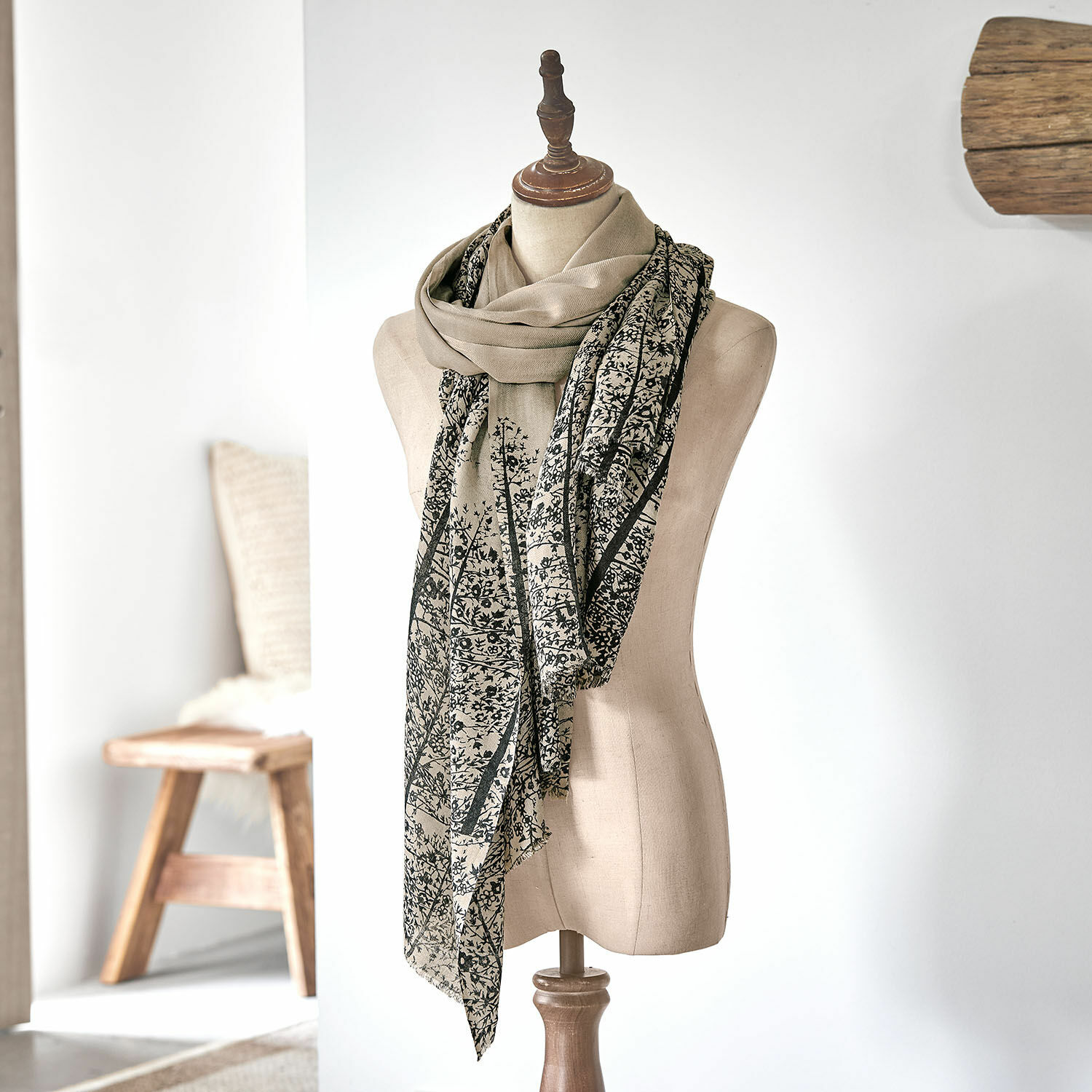 Sjaal Daralon Beige sjaal met zwart plantenpatroon op paspop in lichte kamer, licht en modieus accessoire