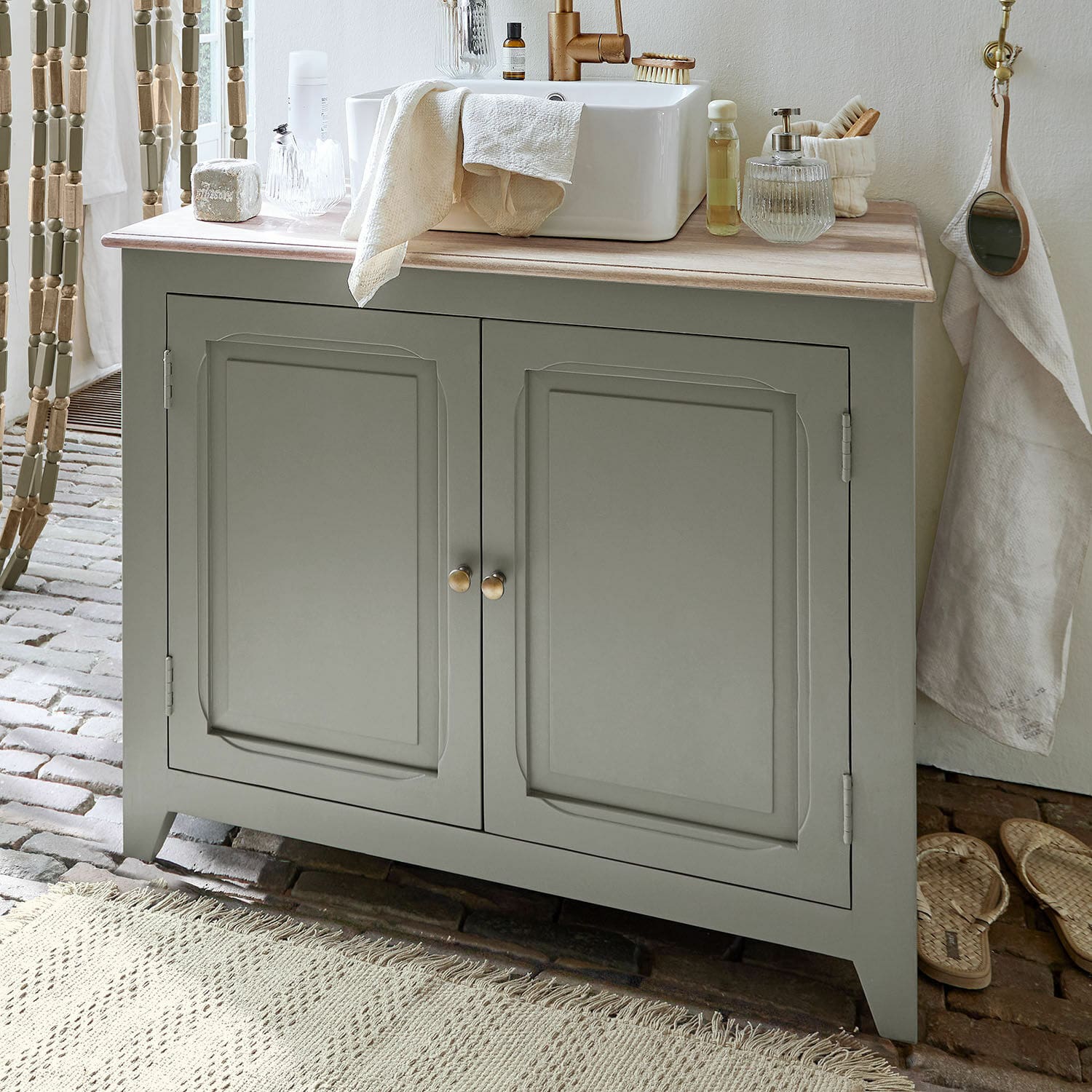 Meuble et vasque Bastanès Meuble de salle de bain gris avec plan en bois et lavabo blanc, accessoires de salle de bain posés dessus