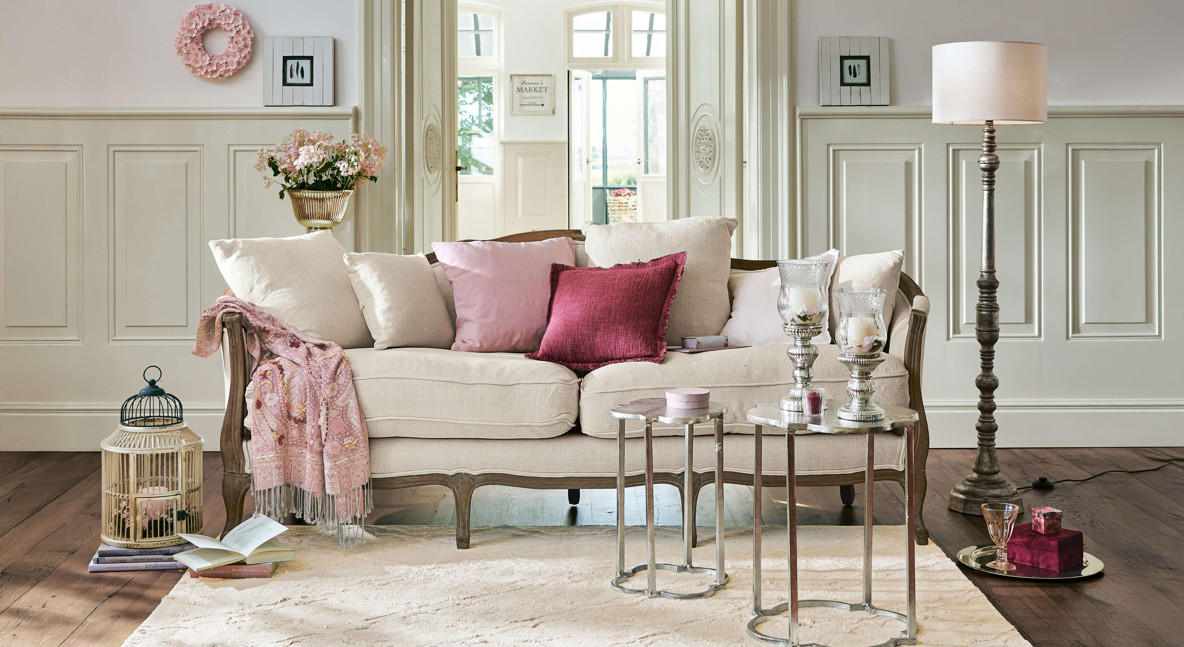Canapé beige avec cadre en bois et coussins roses dans un salon élégant avec décorations