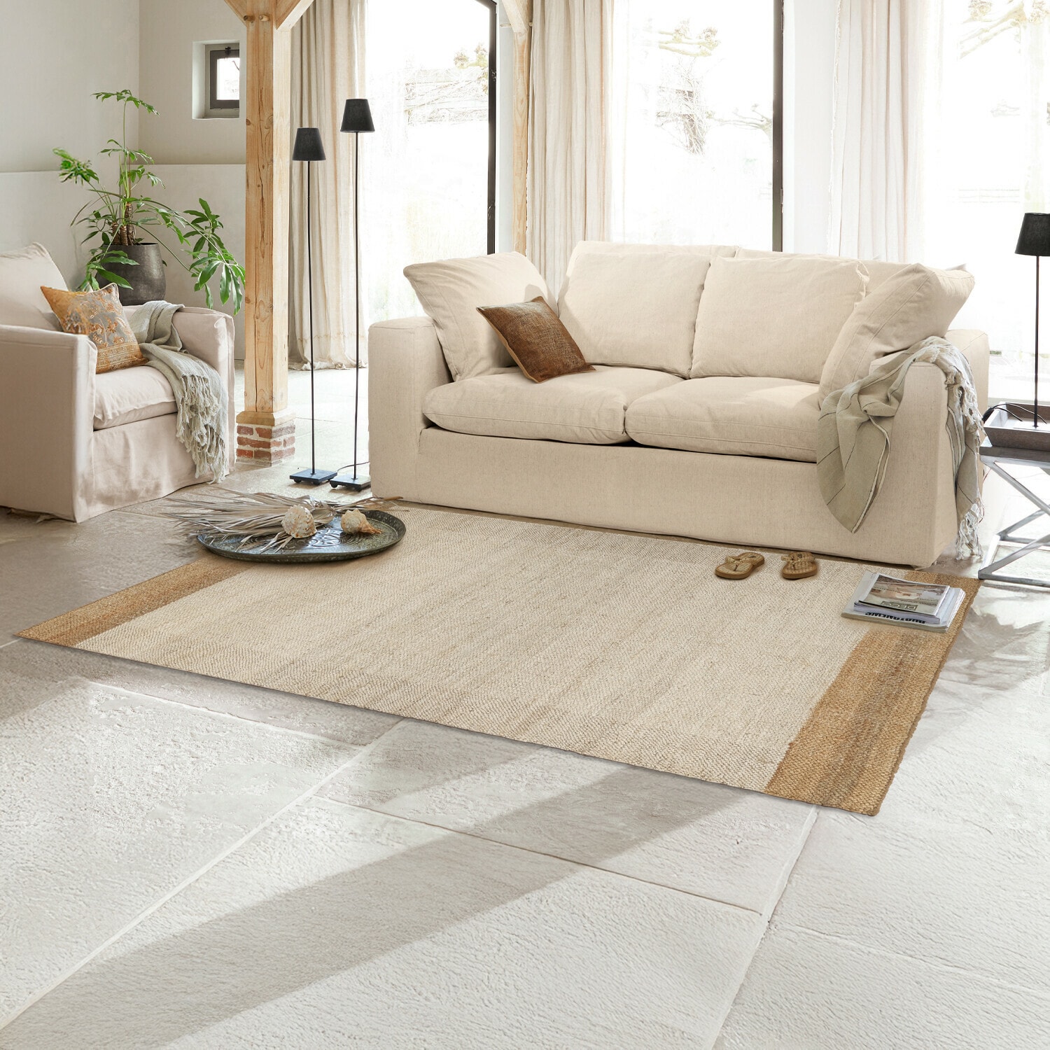 Vloerkleed Estelune Beige vloerkleed van natuurlijk materiaal in lichte woonkamer met bank en fauteuils, interieurdecoratie