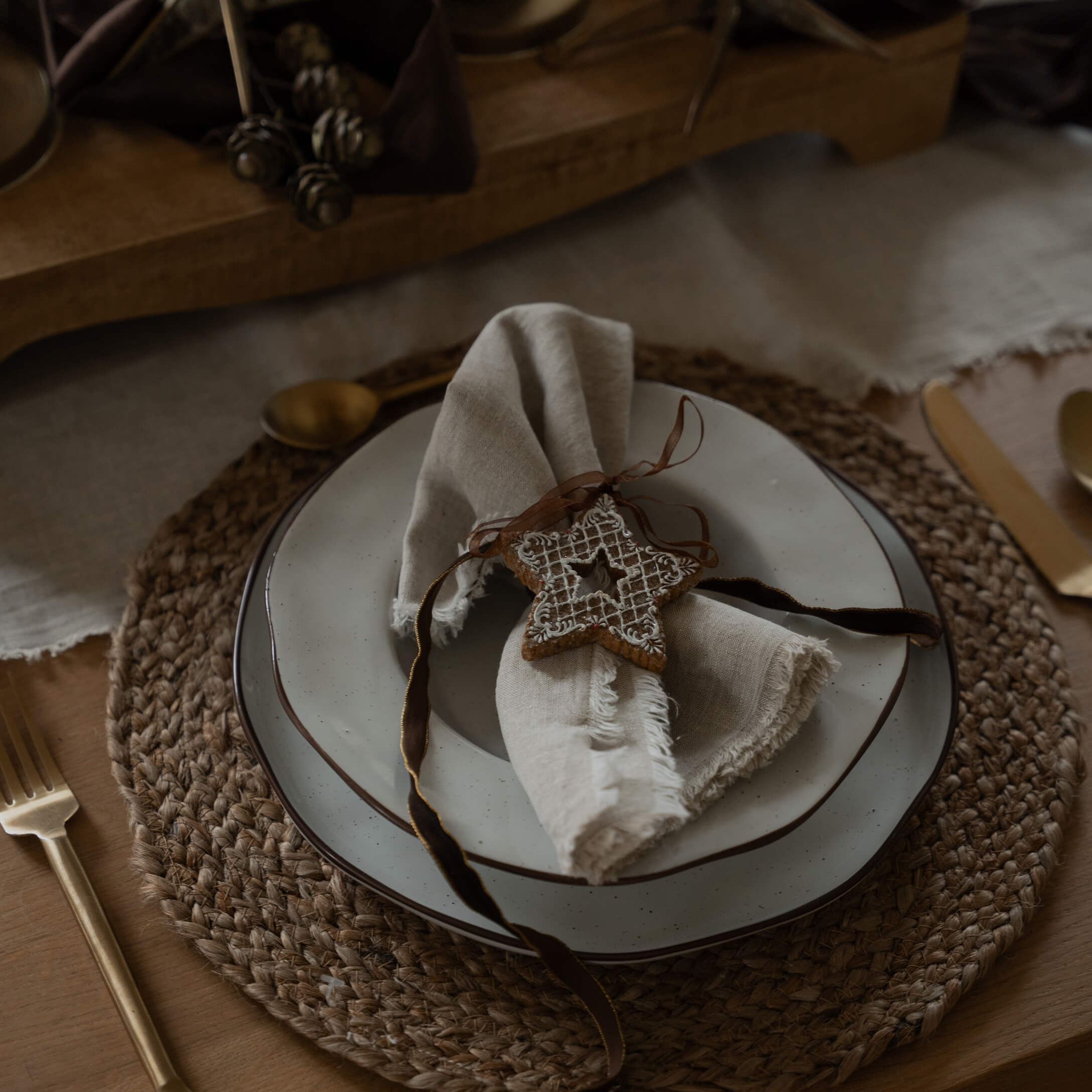Table rustique avec napperon tressé, assiette blanche et serviette en lin ornée d'une étoile décorative