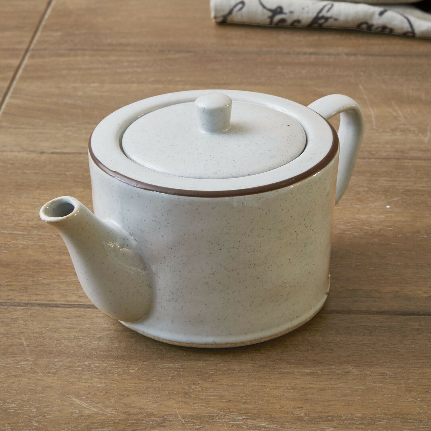 Théière Biarré Théière en céramique blanche avec bordure marron posée sur une table en bois pour infusion de thé