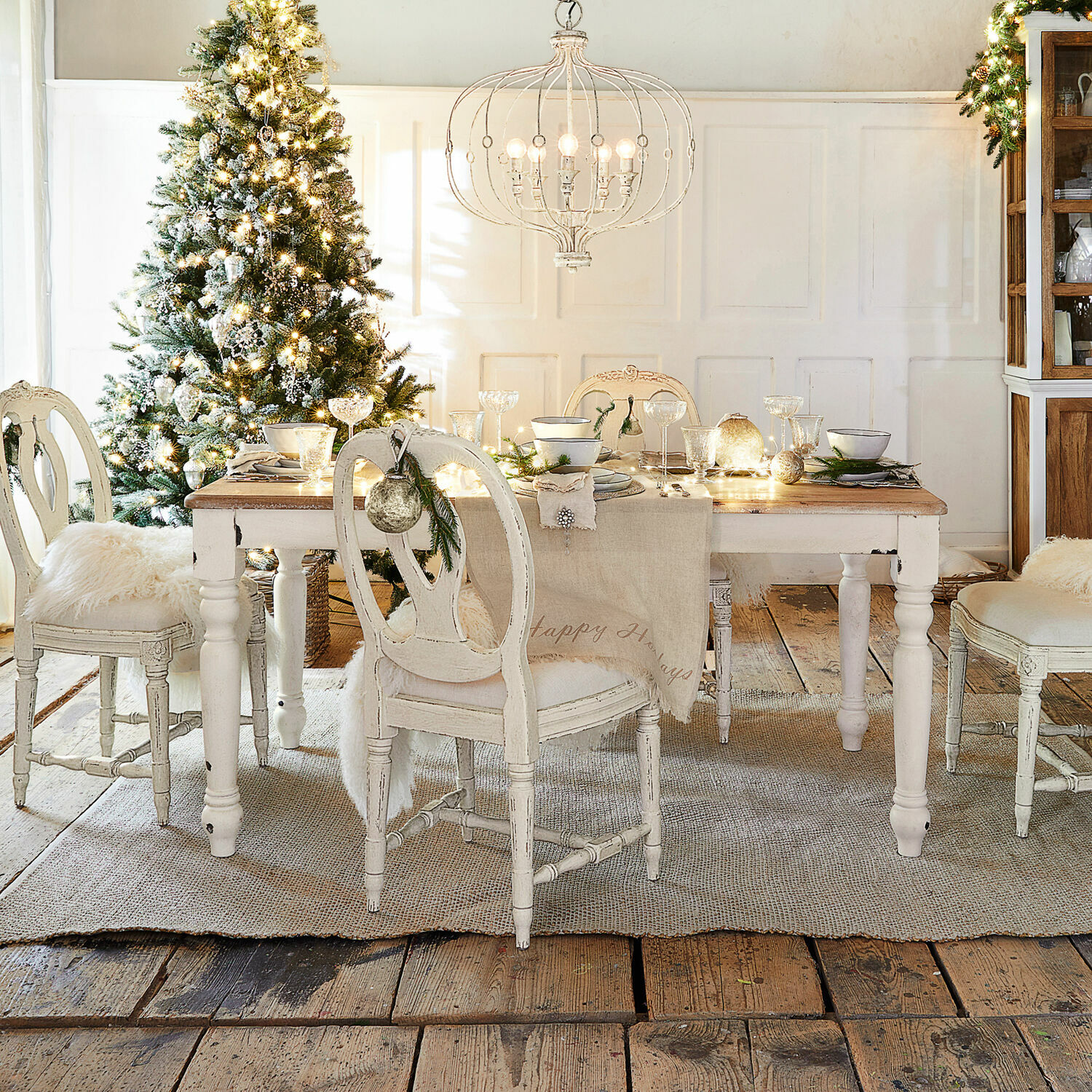 Tafel Mont Lisan Eetkamer met witte houten tafel en stoelen, feestelijk versierd met kerstboom en lamp