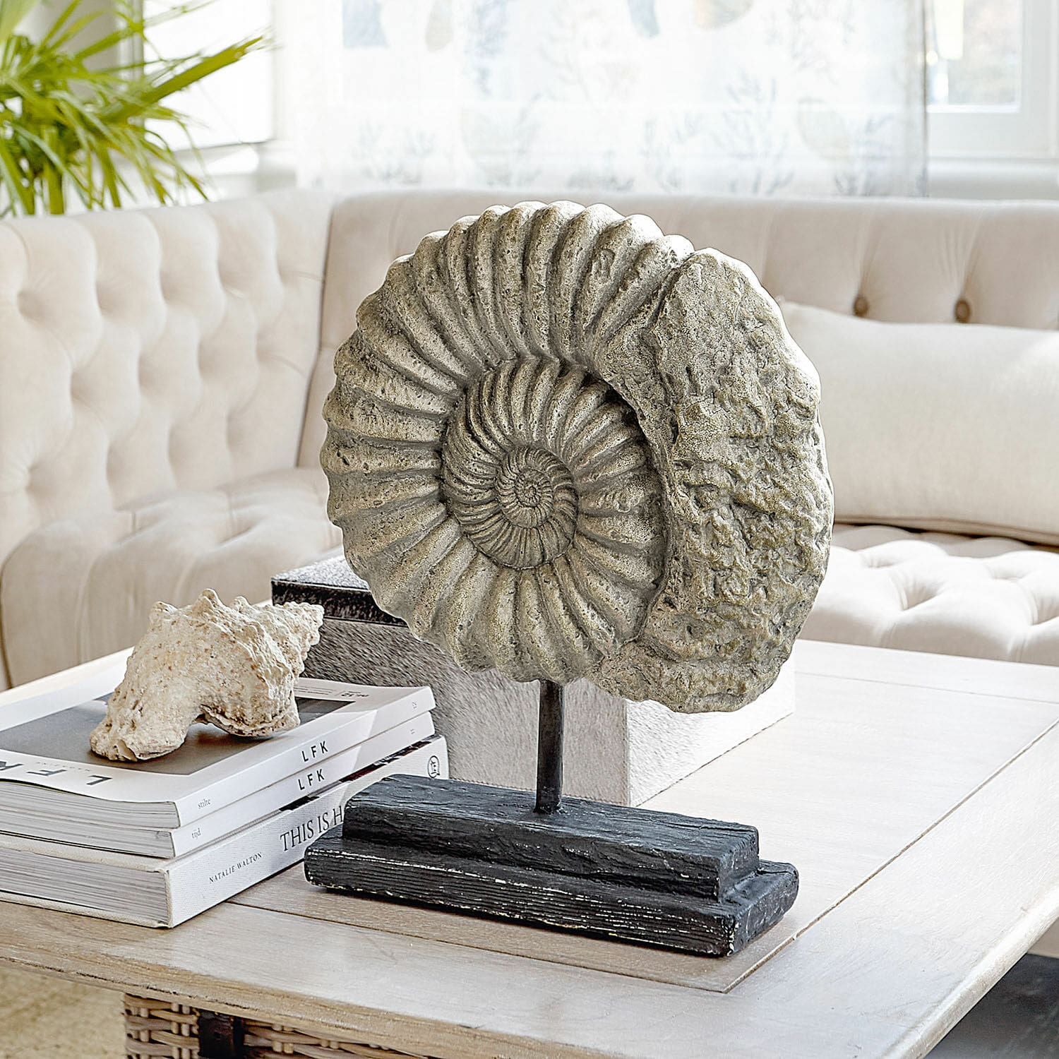 Objet décoratif Dewey Sculpture décorative en forme d'ammonite en pierre sur socle noir posée sur une table basse