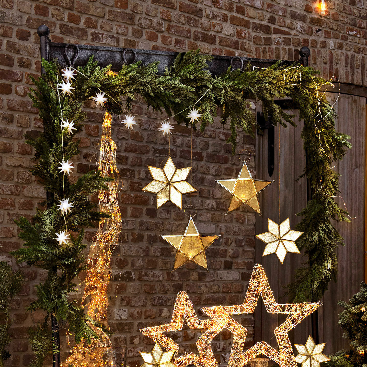 Guirlande Julien Décoration de Noël avec étoiles LED et branches vertes sur mur en briques, éclairage festif chaleureux