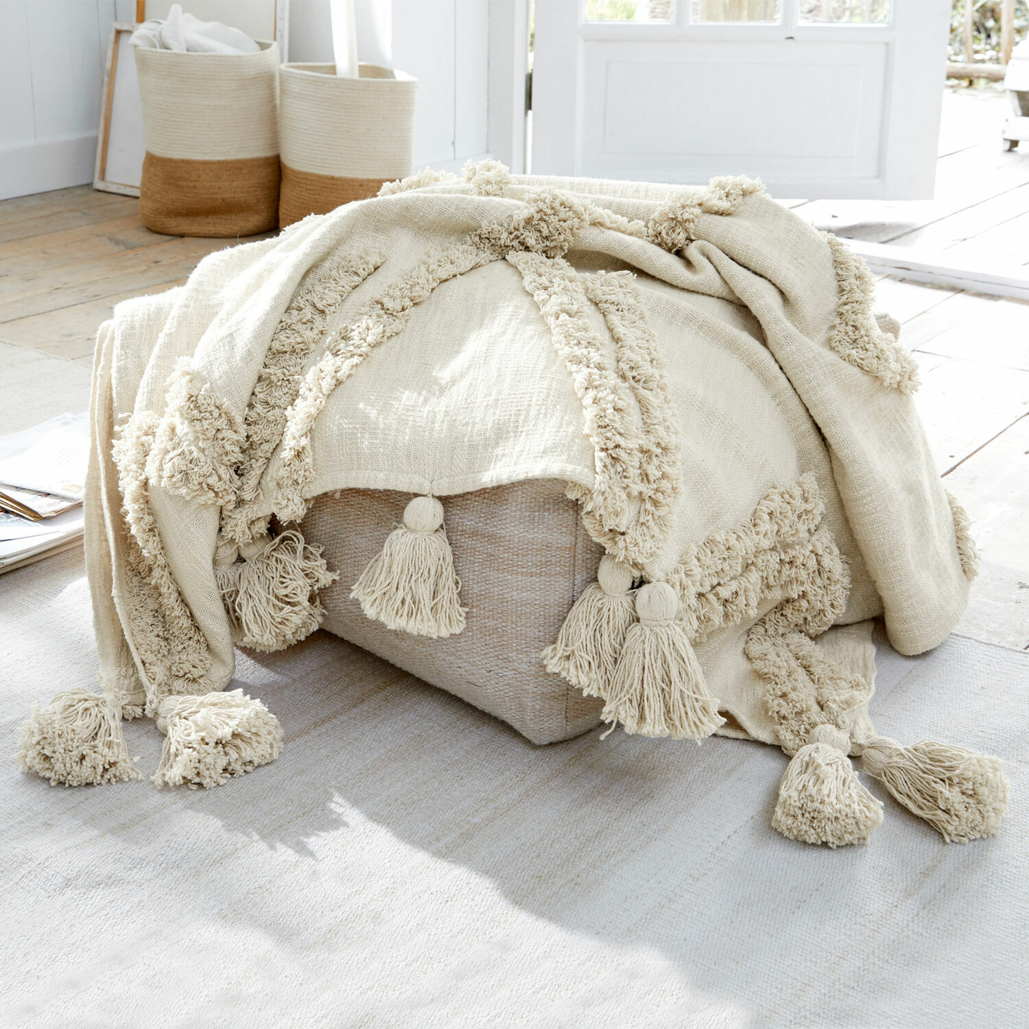 Plaid Linares Beige katoenen deken met kwastjes op lichte poef in natuurlijk lichte kamer