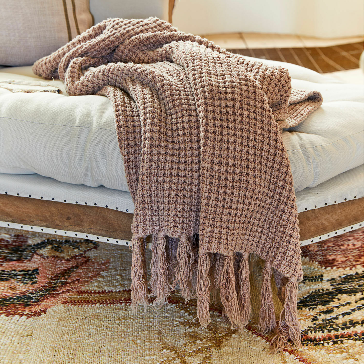 Plaid Kendall Bruine deken met franjes op wit kussen op houten bank, zacht materiaal voor woonkamer