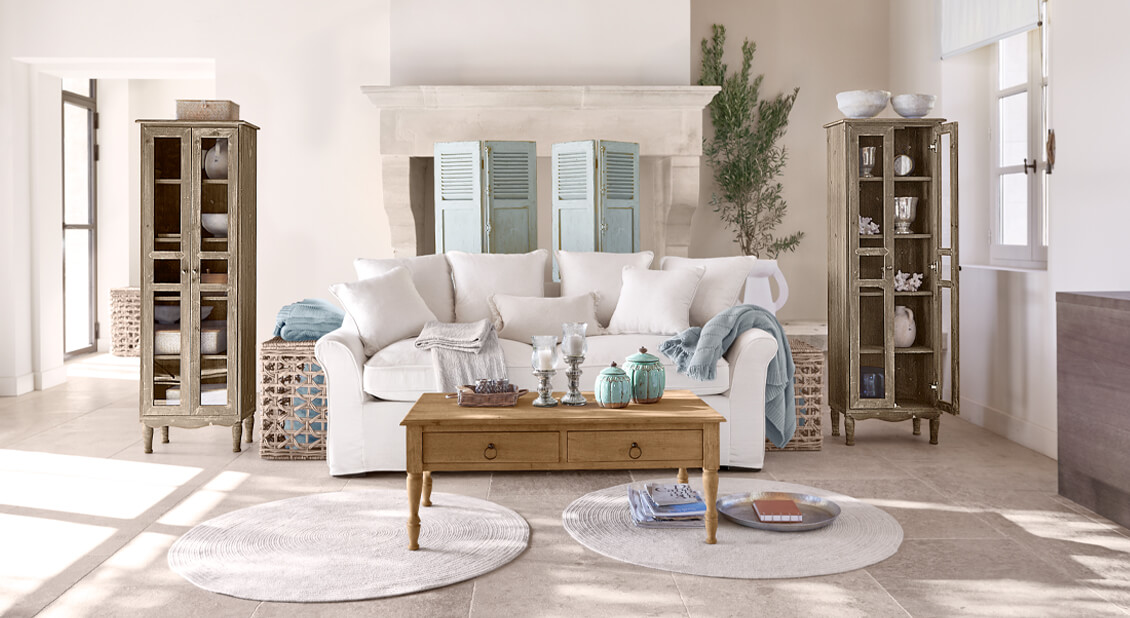 Canapé blanc en coton style marin avec table basse en bois et décorations dans un salon lumineux