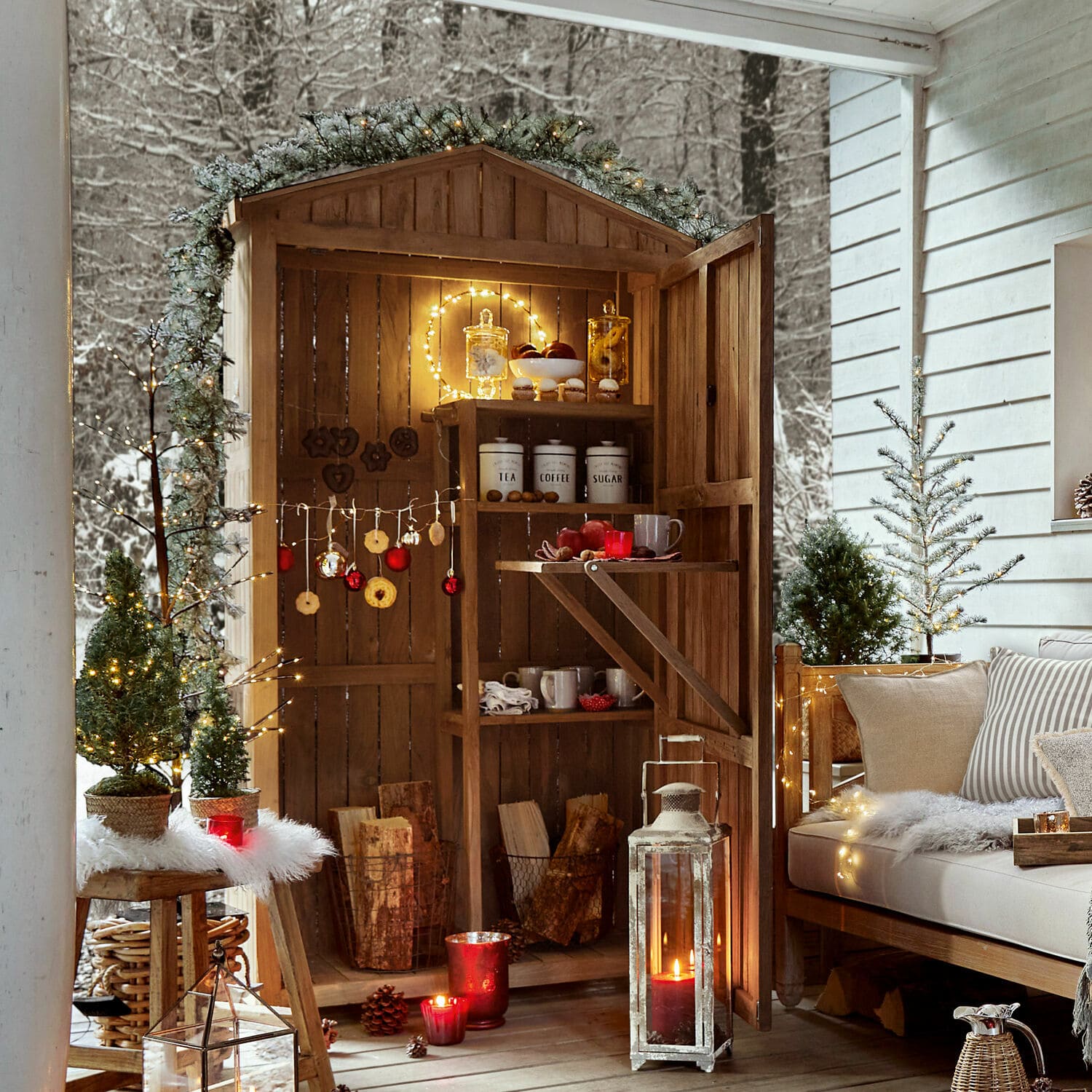 Armoire de jardin Tomte Abri en bois avec étagères décorées de guirlandes lumineuses et décorations de Noël sur une terrasse hivernale
