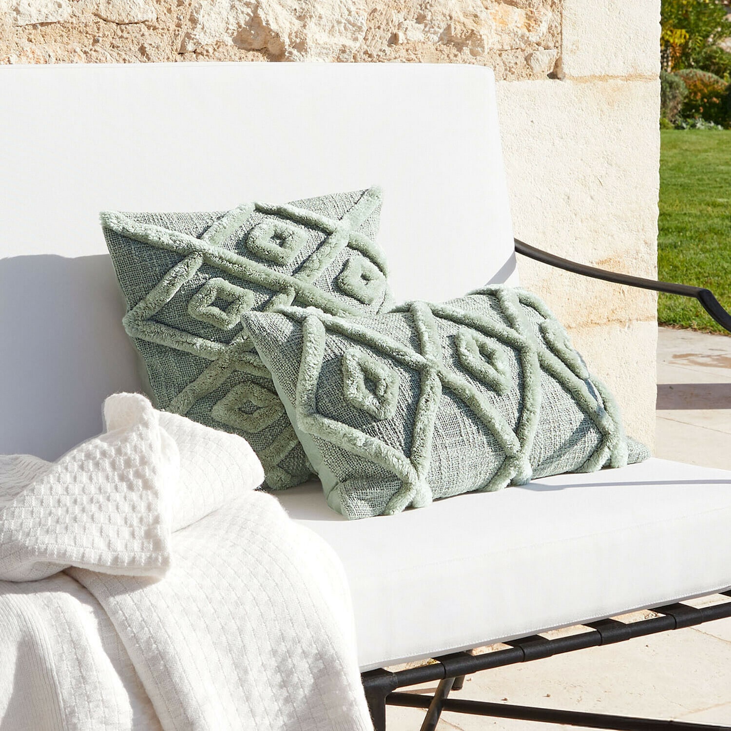 Mintgroene sierkussens met geometrisch patroon op witte bank met deken, woontextiel