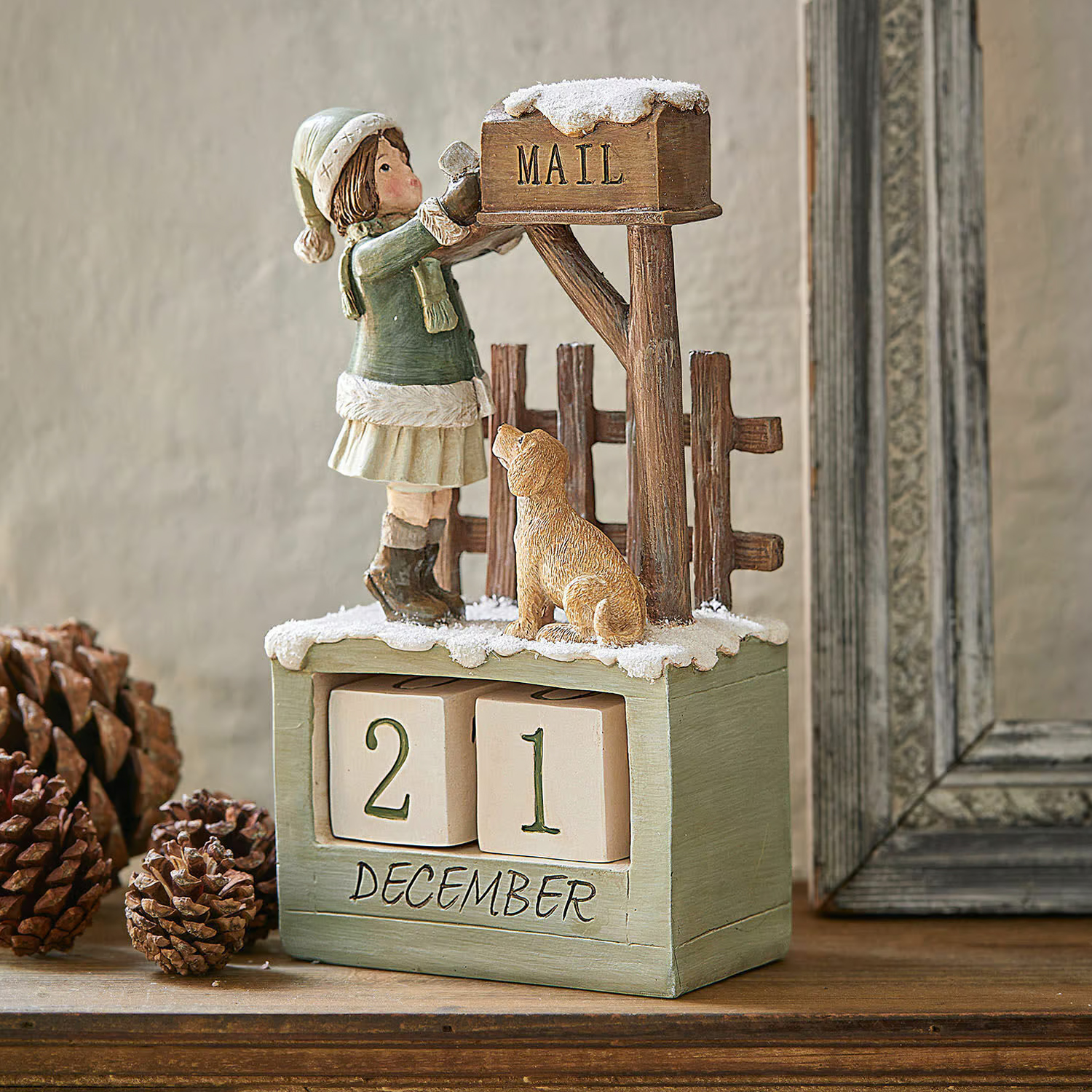 Calendrier en bois avec figurine de fille et chien près d'une boîte aux lettres enneigée pour décoration hivernale