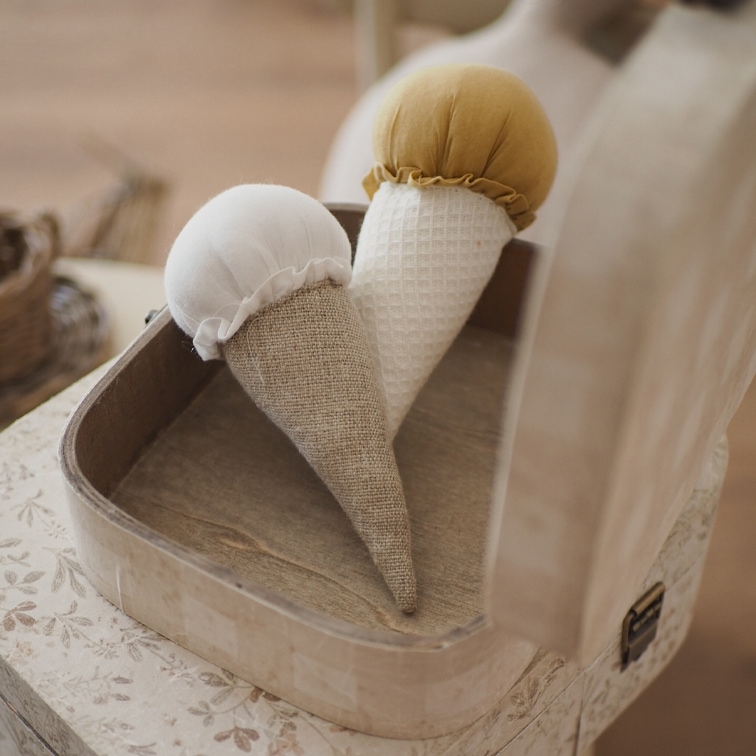 Twee decoratieve stoffen kegels in wit en mosterdkleur in een houten doos op tafel
