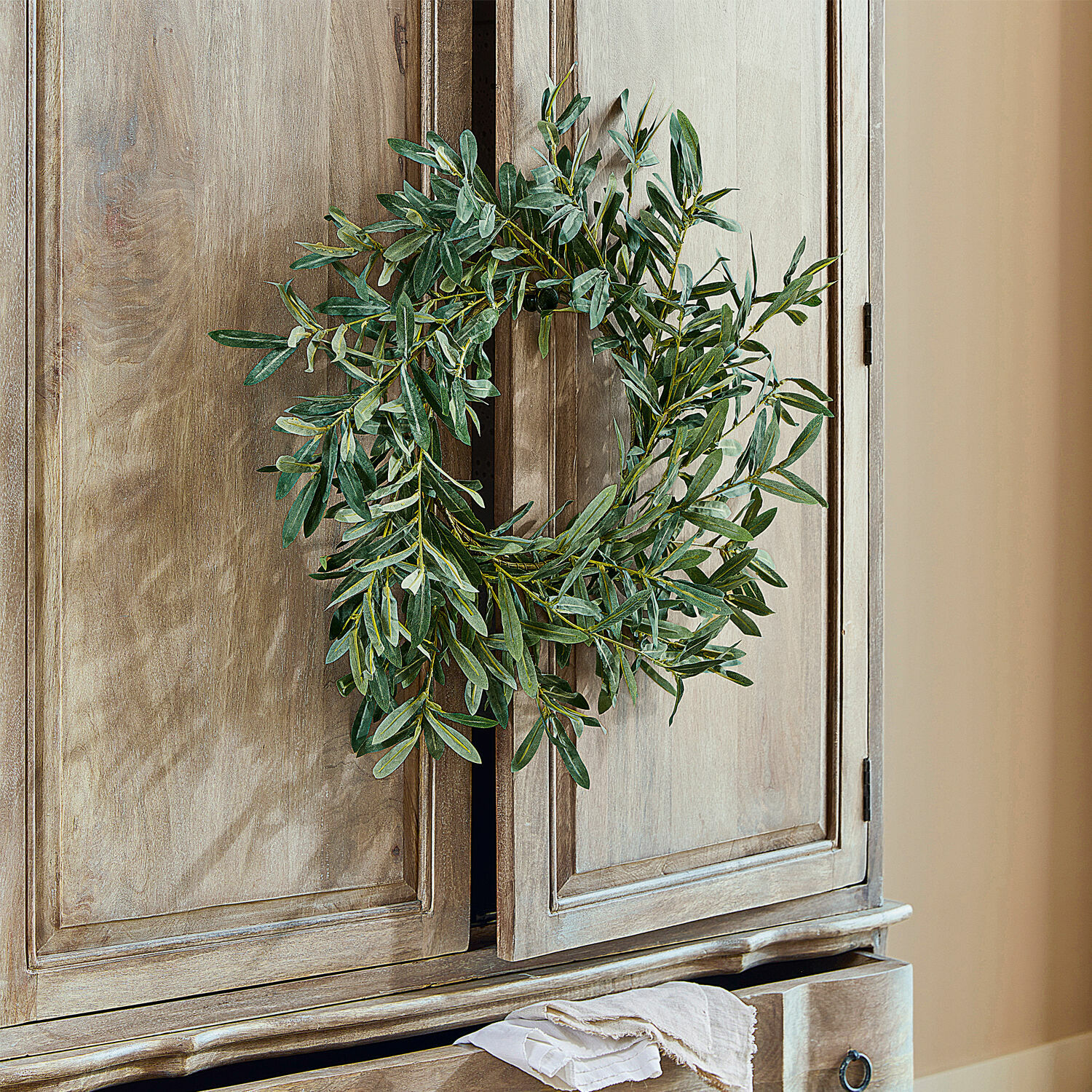 Krans Zoey Decoratieve krans van groene bladeren aan een kast van natuurlijk gekleurd hout