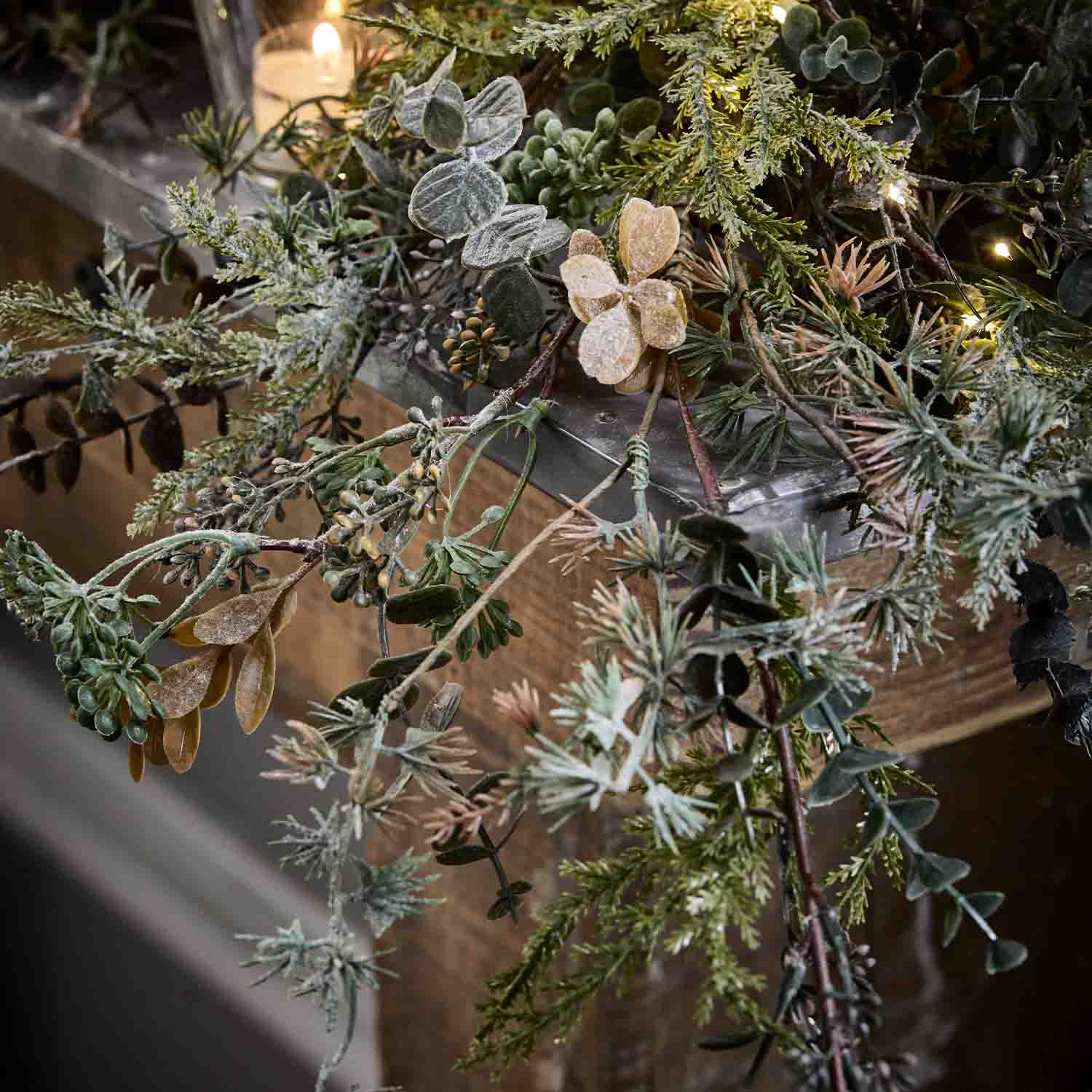 Decoratieve krans van groene en beige takken met zachte LED-verlichting op houten achtergrond