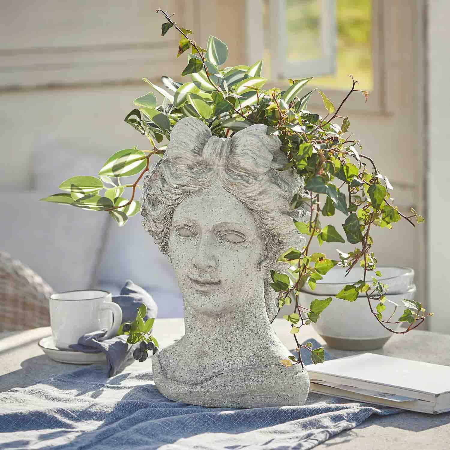 Cache-pot en forme de tête de femme en pierre grise avec plantes vertes, décoration d'extérieur