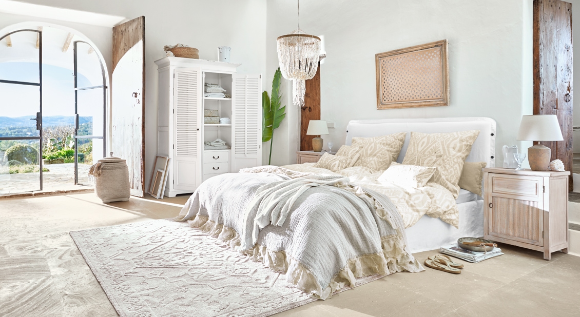 Lichte slaapkamer met wit bed, beige beddengoed en rustieke houten meubels