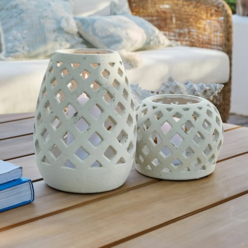 Deux lanternes blanches en céramique avec motif ajouré sur une table en bois, décoration extérieure