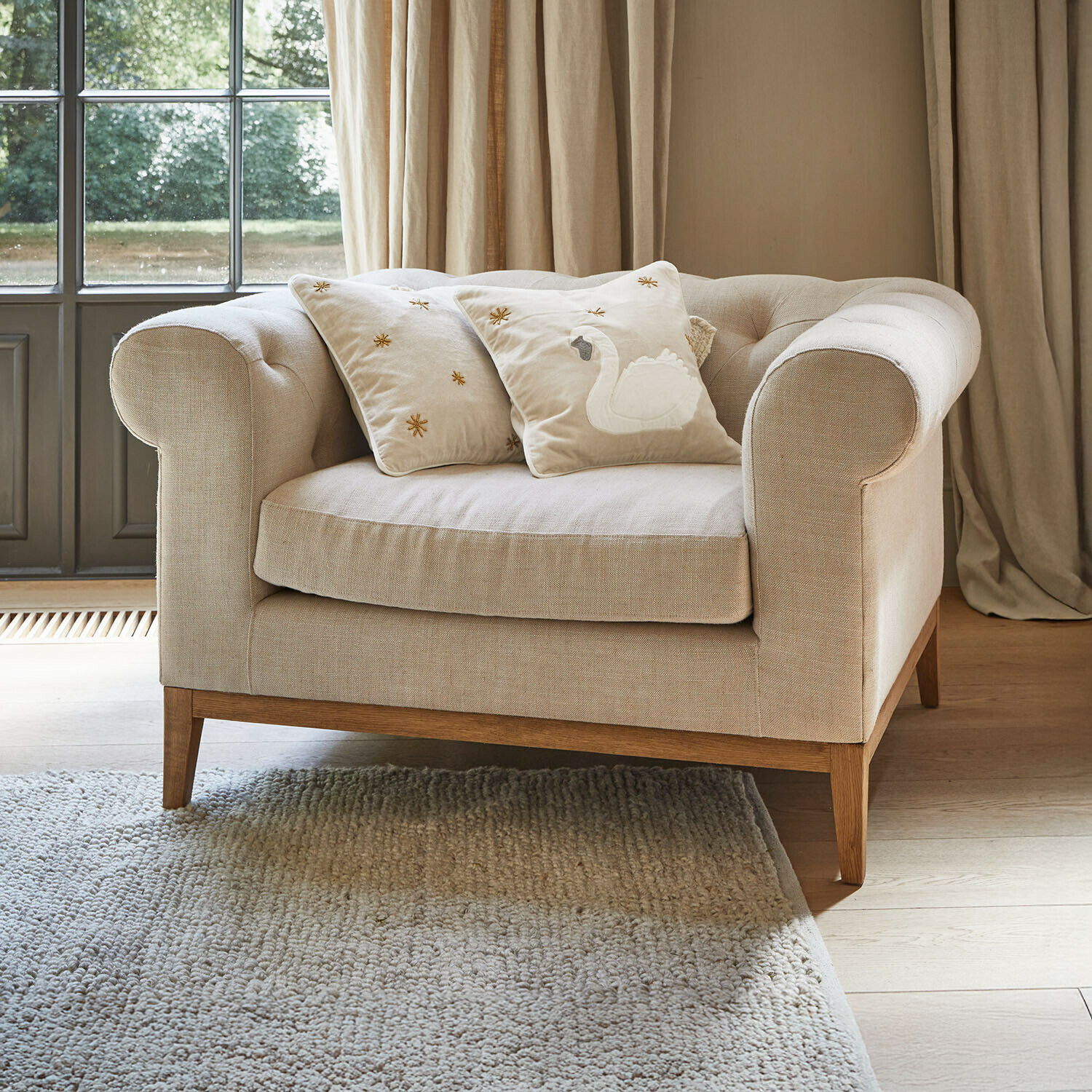 Fauteuil Fairbourne Beige stoffen bank met houten onderstel en twee sierkussens met zwaanborduursel