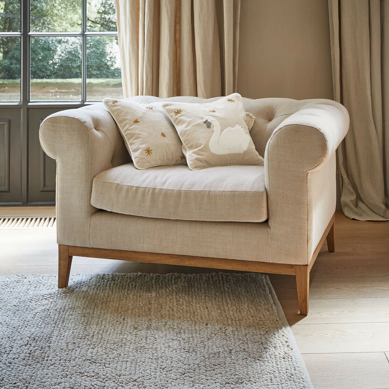 Fauteuil Fairbourne Beige stoffen bank met houten onderstel en twee sierkussens met zwaanborduursel