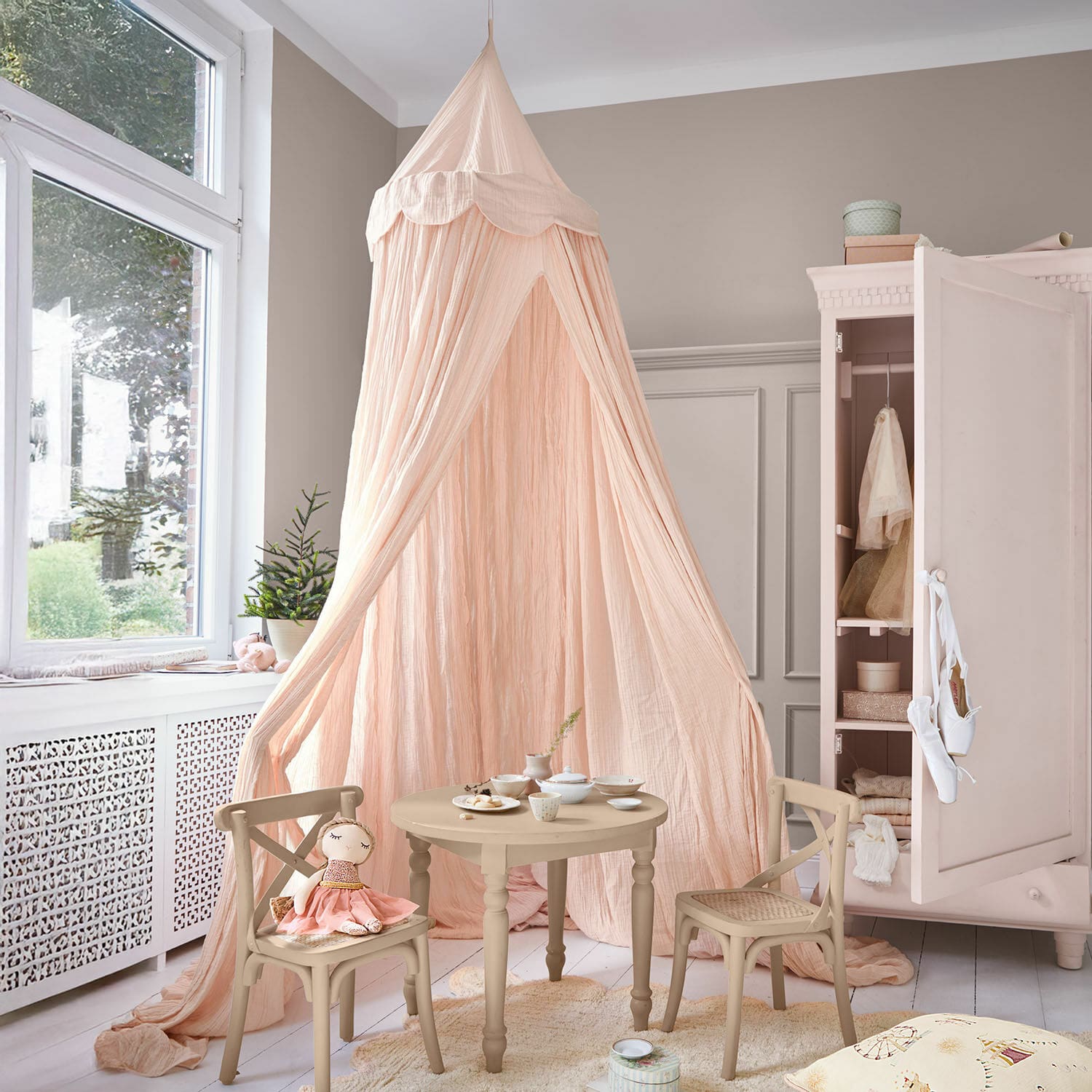 Bedhemel Larika Kinderkamer met beige houten tafel en stoelen en een roze stoffen hemelbed