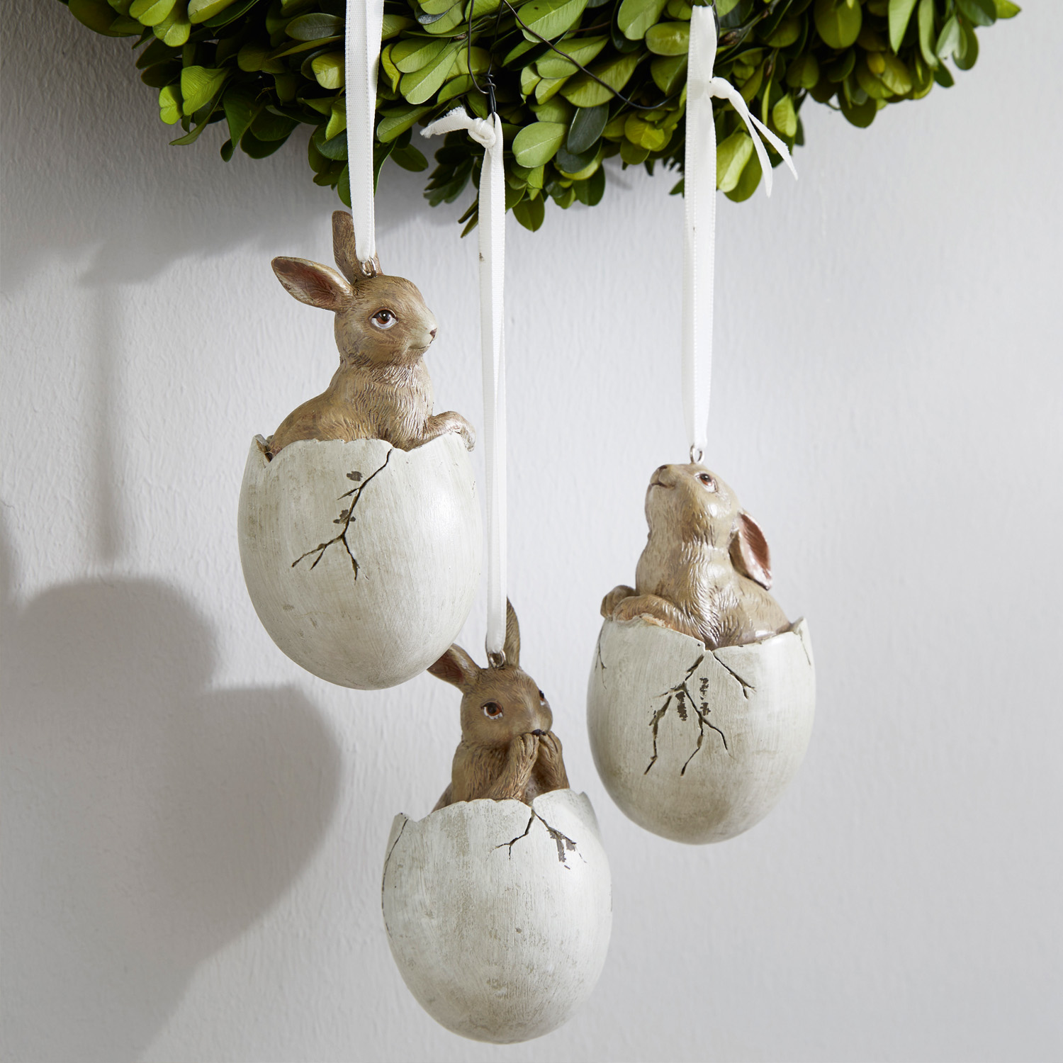 Drie hangende decoraties met konijnen in witte eierschalen, paasversiering