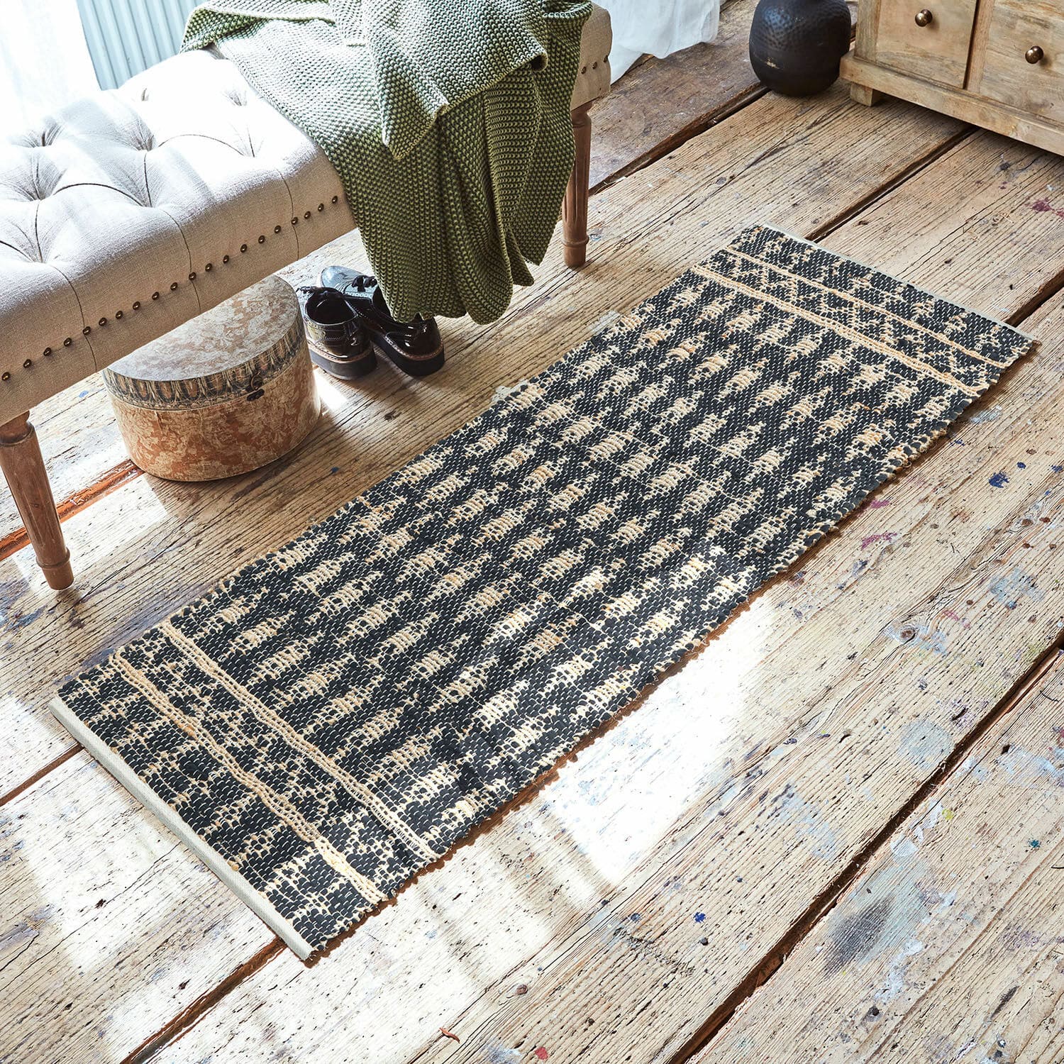 Tapis long Frizzy Tapis noir et beige en matériau naturel sur un sol en bois dans un intérieur chaleureux