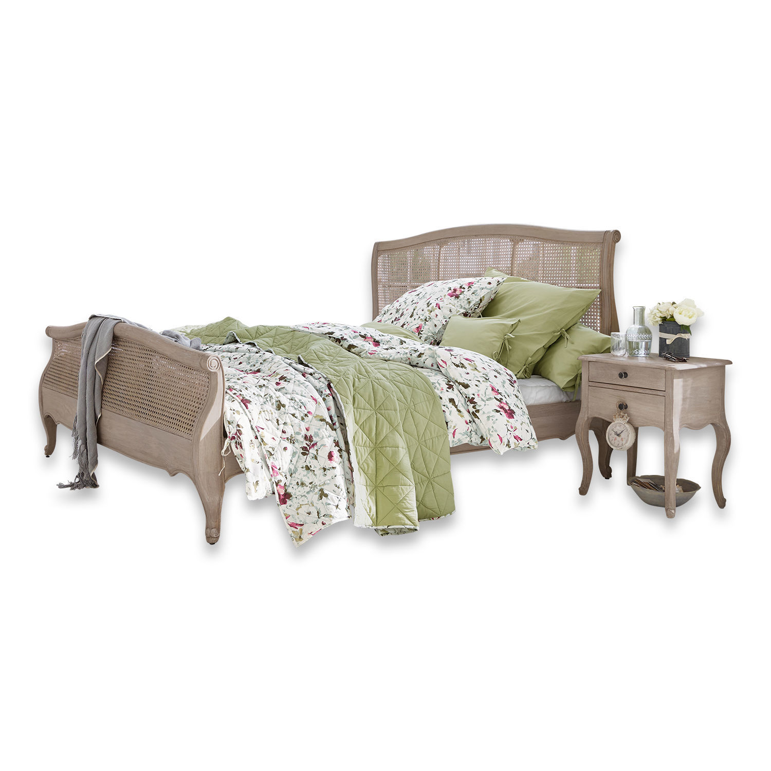 Lit en bois et rotin naturel avec literie verte et à fleurs dans un style vintage élégant