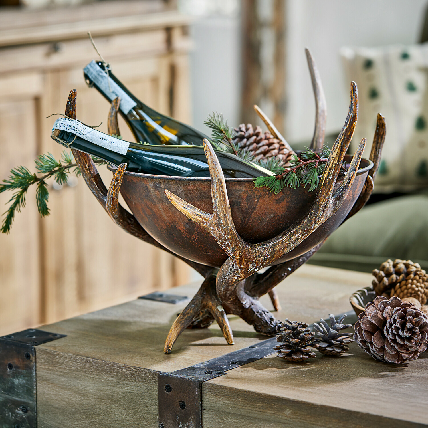 Coupe décorative Morlaix Bol rustique en métal brun avec imitation bois de cerf, contenant des bouteilles de vin et décoré de pommes de pin
