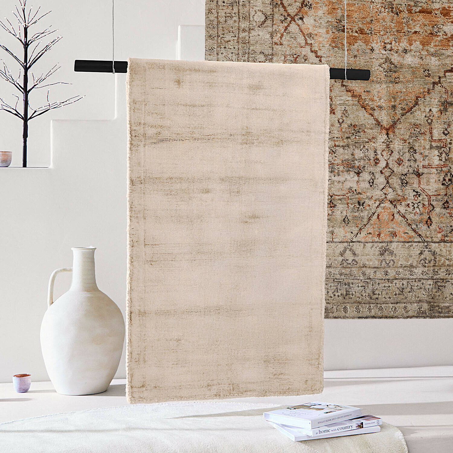 Tapis Mariselle Tapis beige en tissu doux suspendu sur une barre noire dans un intérieur clair avec décorations
