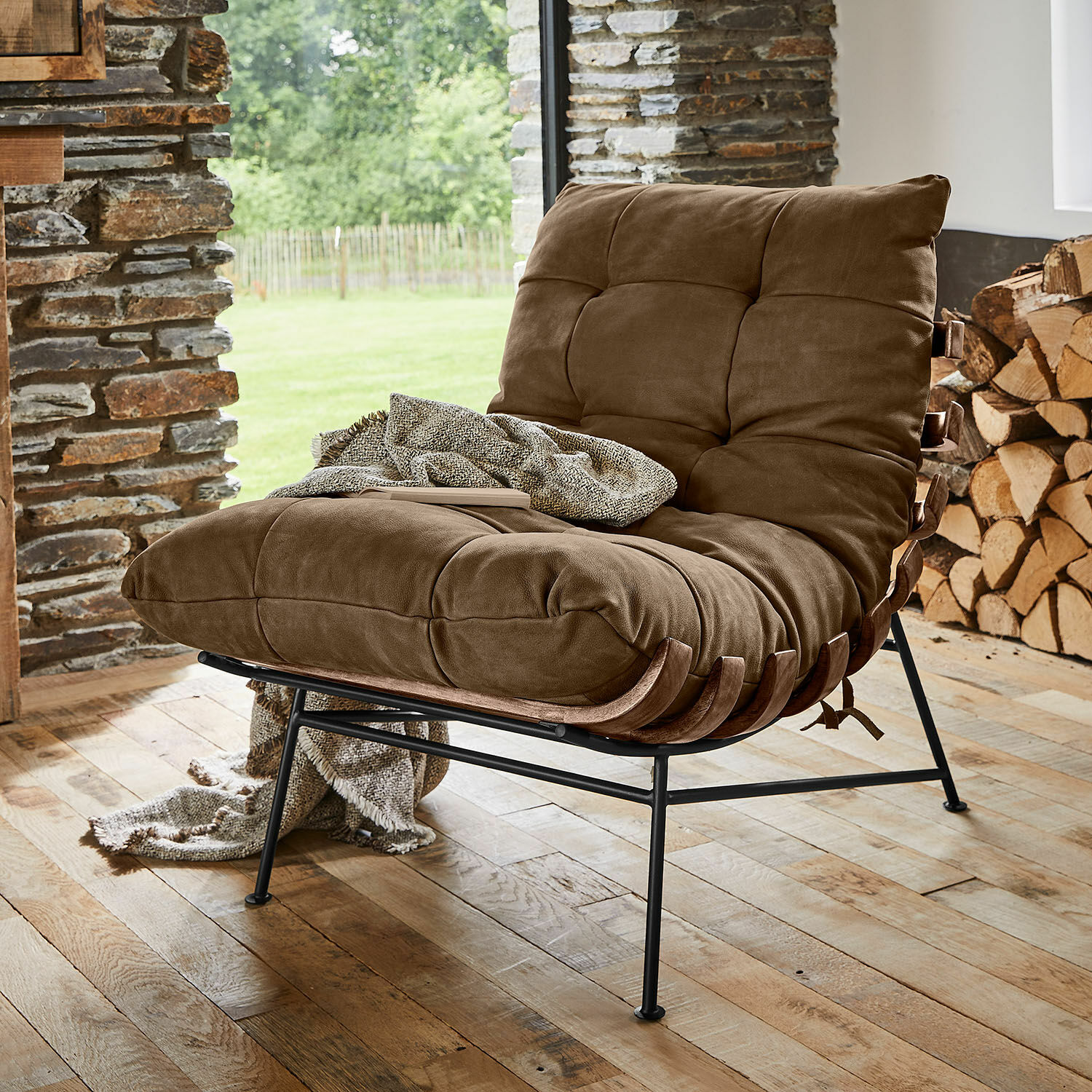 Fauteuil Horraine Fauteuil marron avec rembourrage doux et structure métallique sur parquet en bois dans un intérieur chaleureux