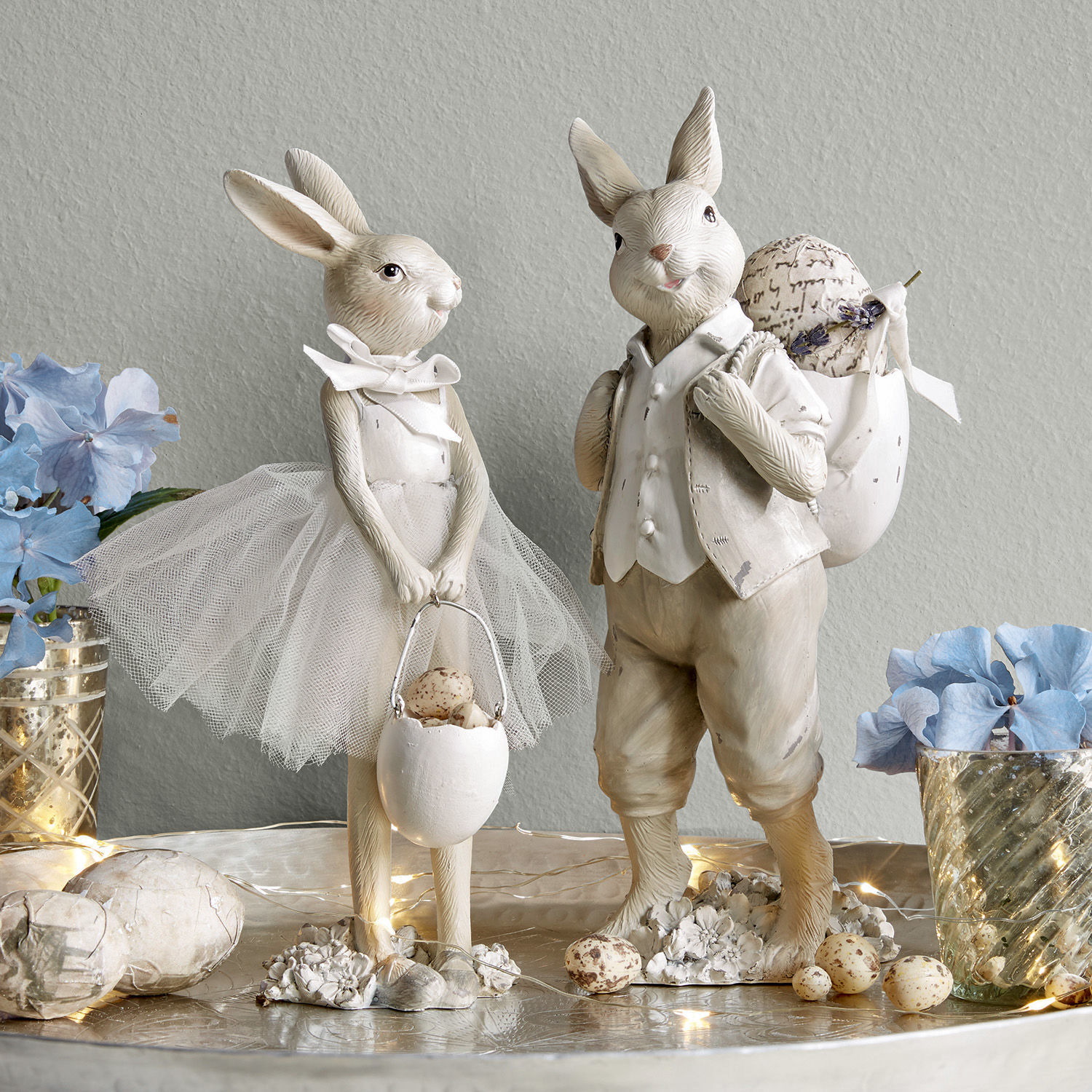 Lot de 2 lapins Perpignan Figurines décoratives de lapins clairs avec accessoires de Pâques et fleurs sur une table