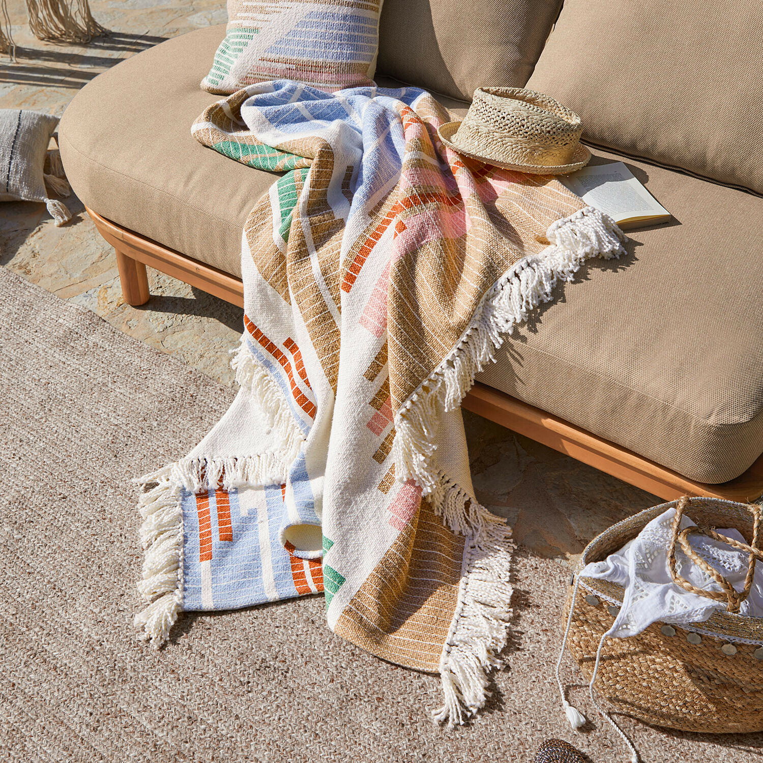 Plaid en coton coloré avec franges sur canapé beige en extérieur, décoration et confort