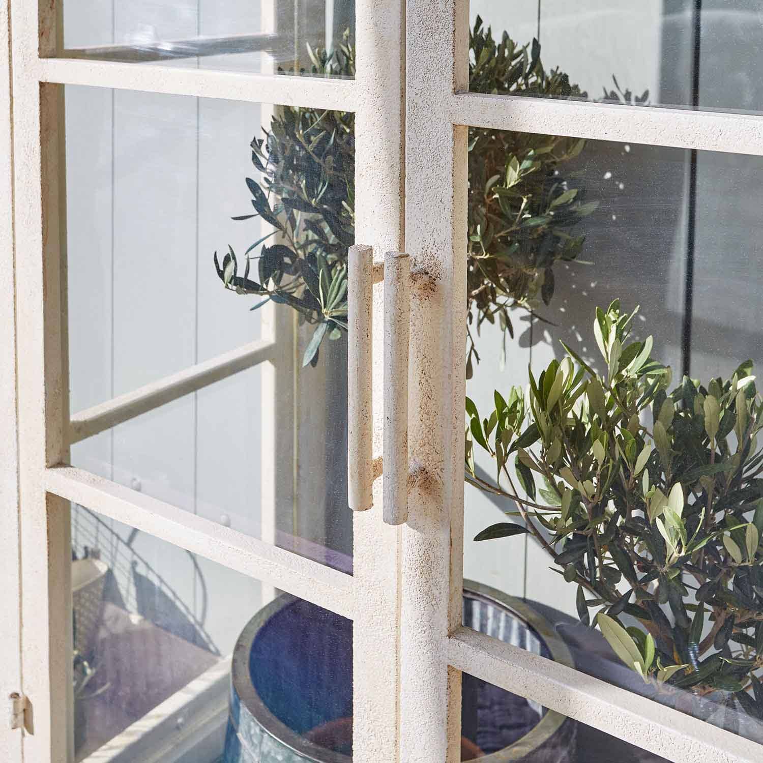 Porte en métal blanc avec poignées et plantes vertes en arrière-plan, décoration extérieure