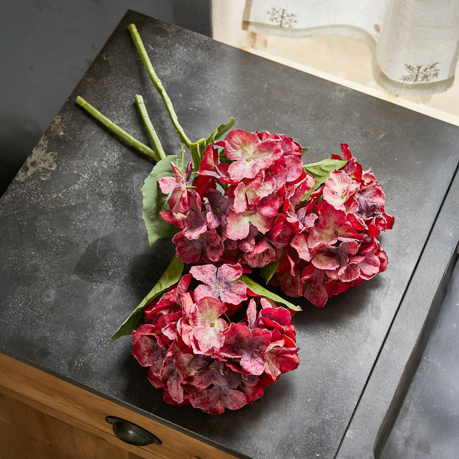 Lot de 3 fleurs décoratives Virette Bouquet d'hortensias artificiels rouge et rose avec feuilles vertes posé sur un plan sombre