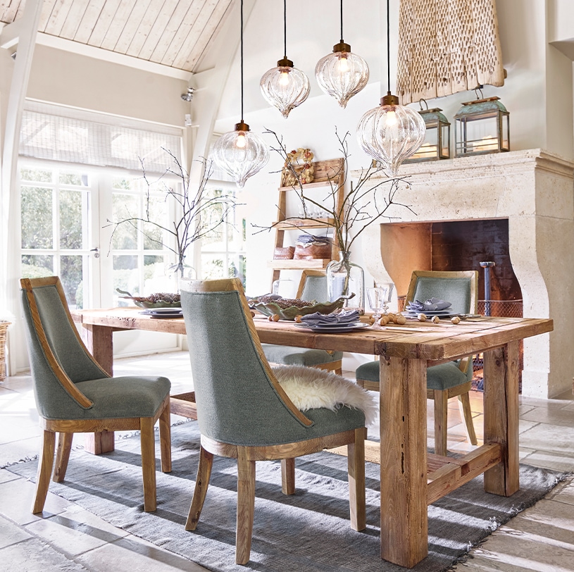 Eetkamer met massief houten tafel en grijze gestoffeerde stoelen, decoratieve glazen hanglampen