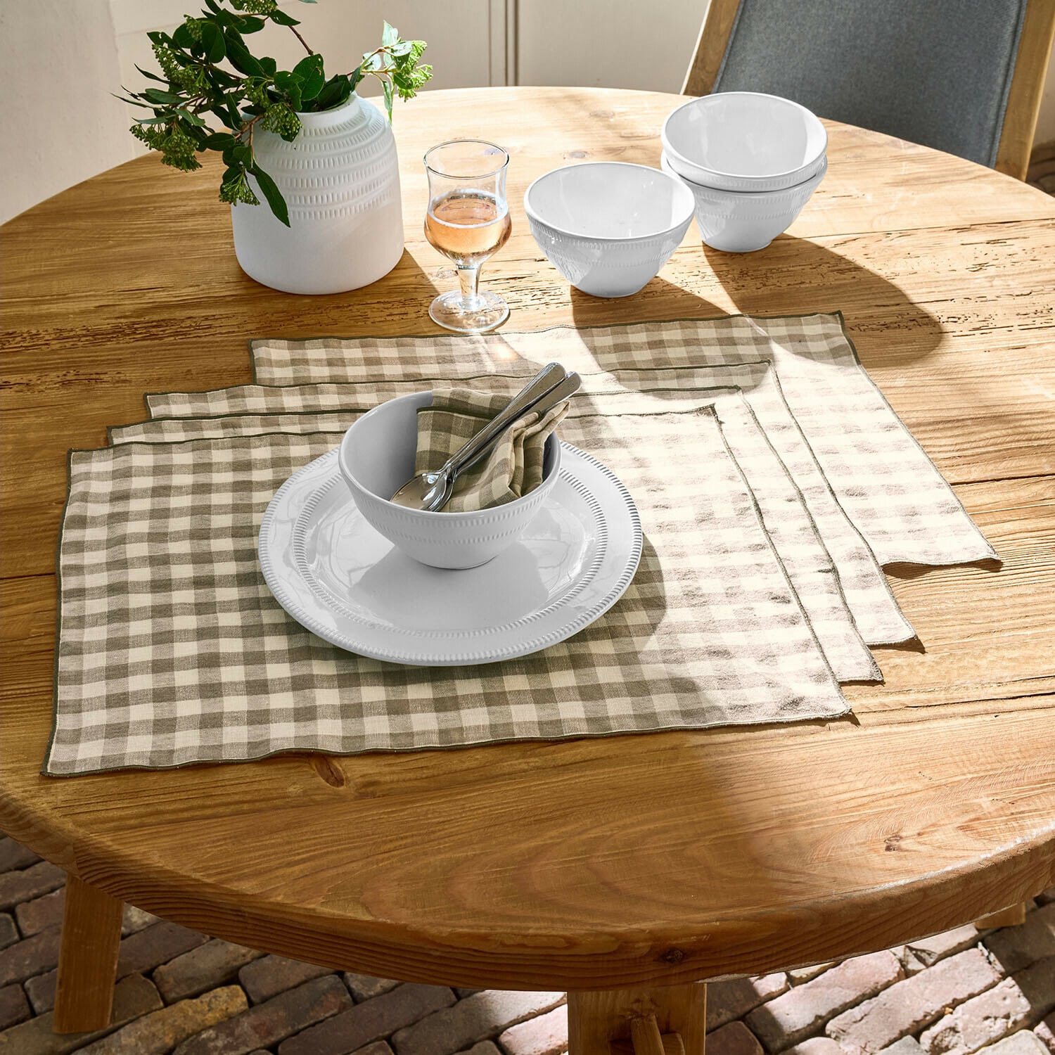 Placemat set van 4 Marrowby Witte keramische kommen en bord op houten tafel met beige-witte linnen placemats in ruitpatroon