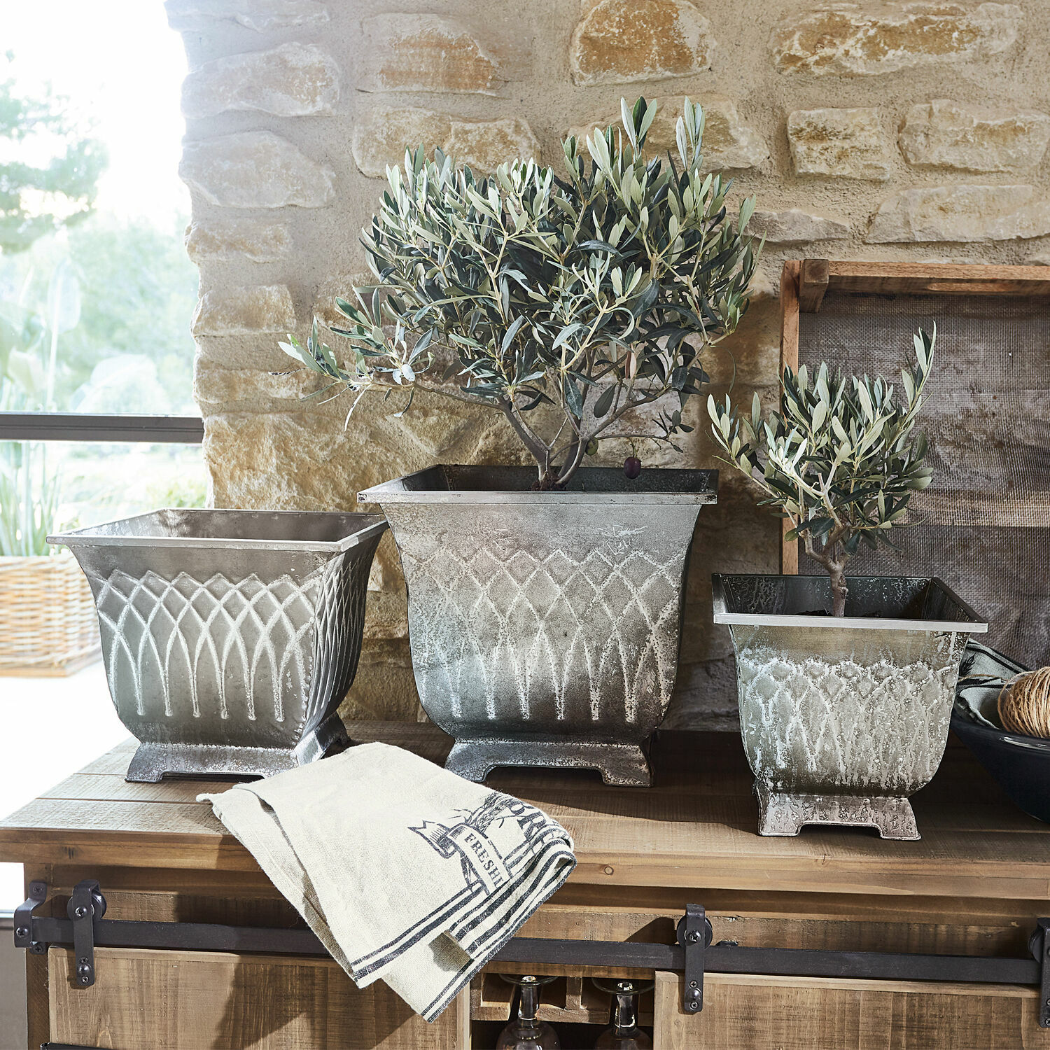 Lot de 3 cache-pots Klaireau Trois pots en métal vintage avec plantes sur une table en bois dans un intérieur lumineux
