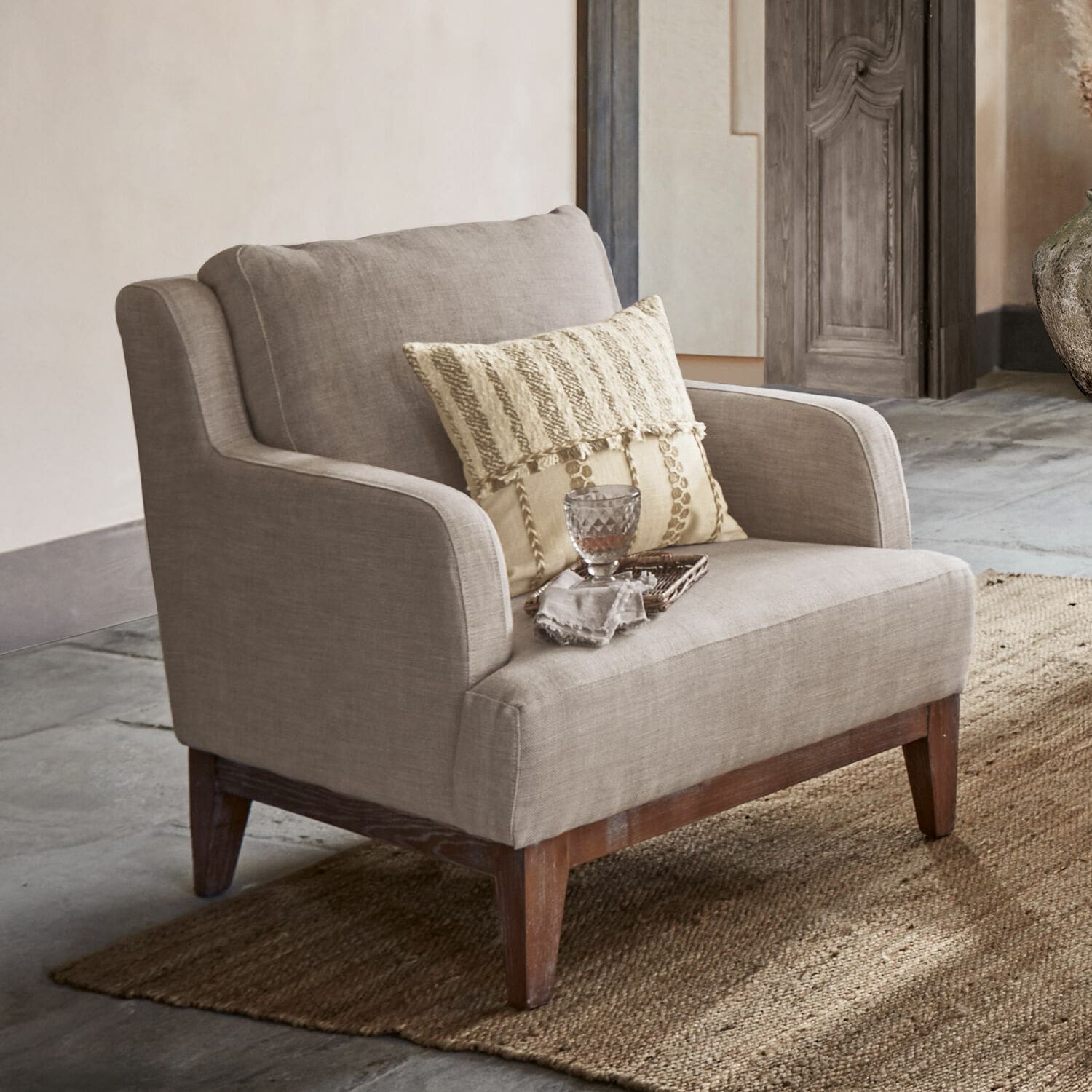 Fauteuil beige en tissu avec pieds en bois sur tapis, meuble élégant pour salon