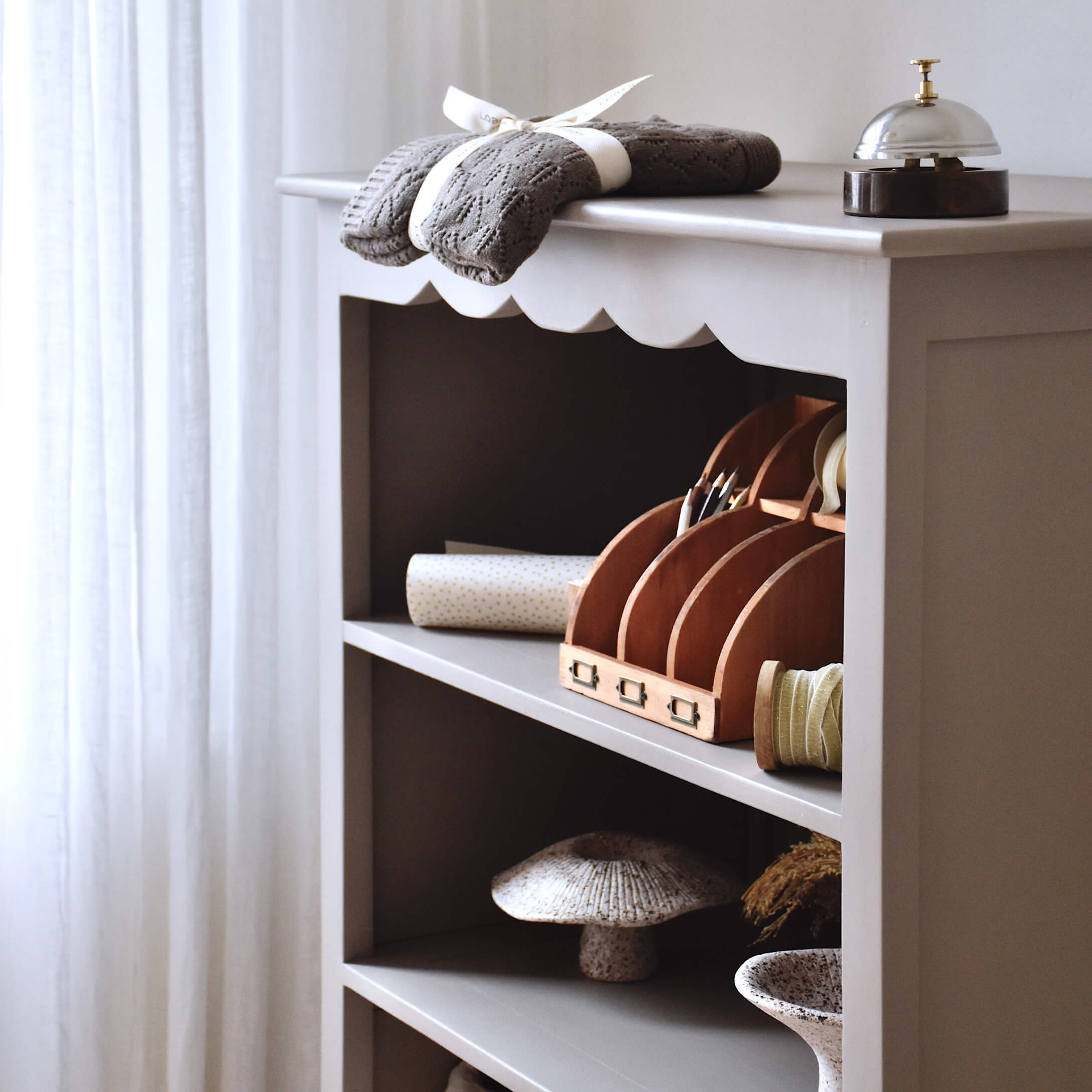 Étagère grise en bois avec objets décoratifs et tissu tricoté gris posé dessus