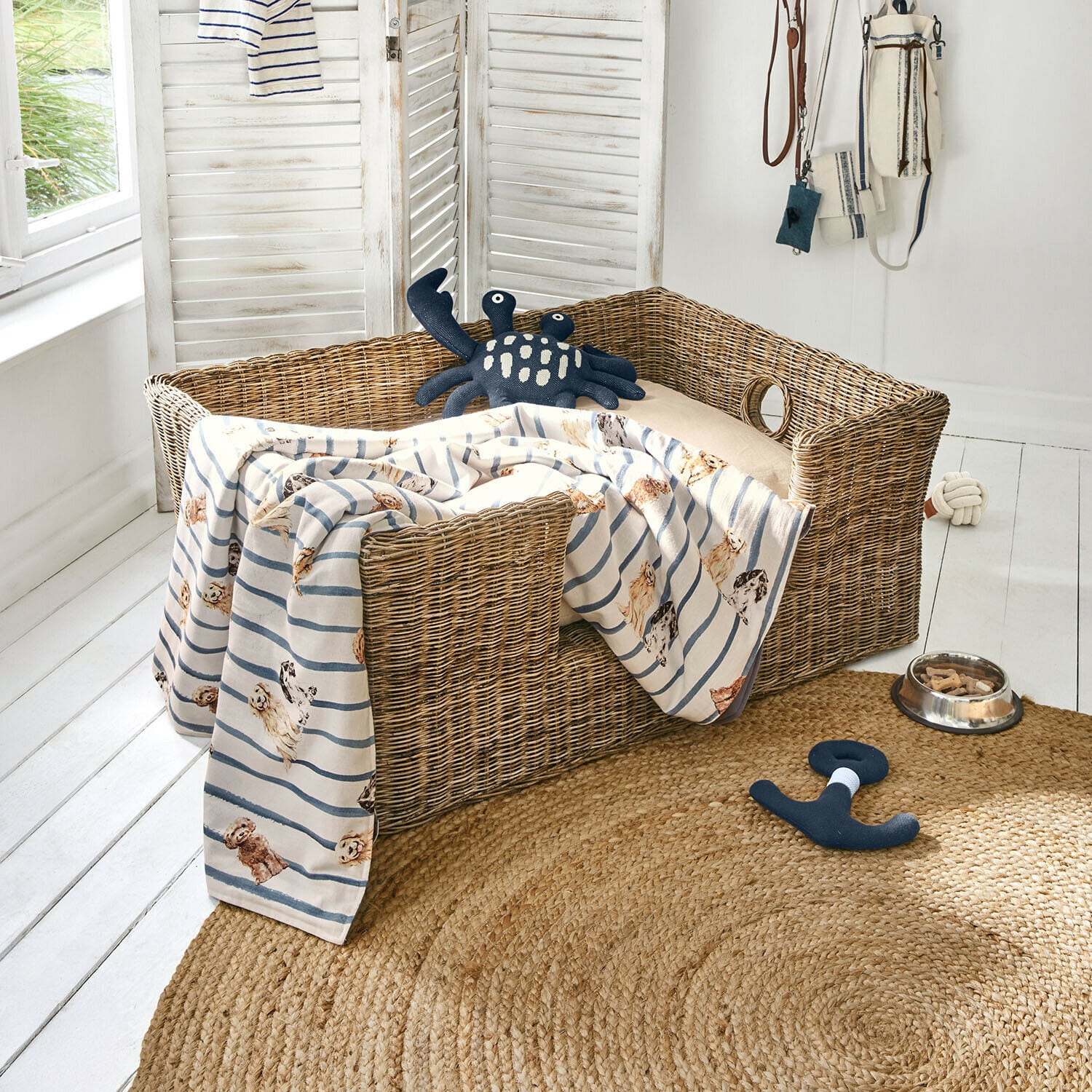 Panier pour animaux Knuddo Panier en osier pour chien avec coussin beige et couverture rayée à motif chiens, jouets et gamelle au sol