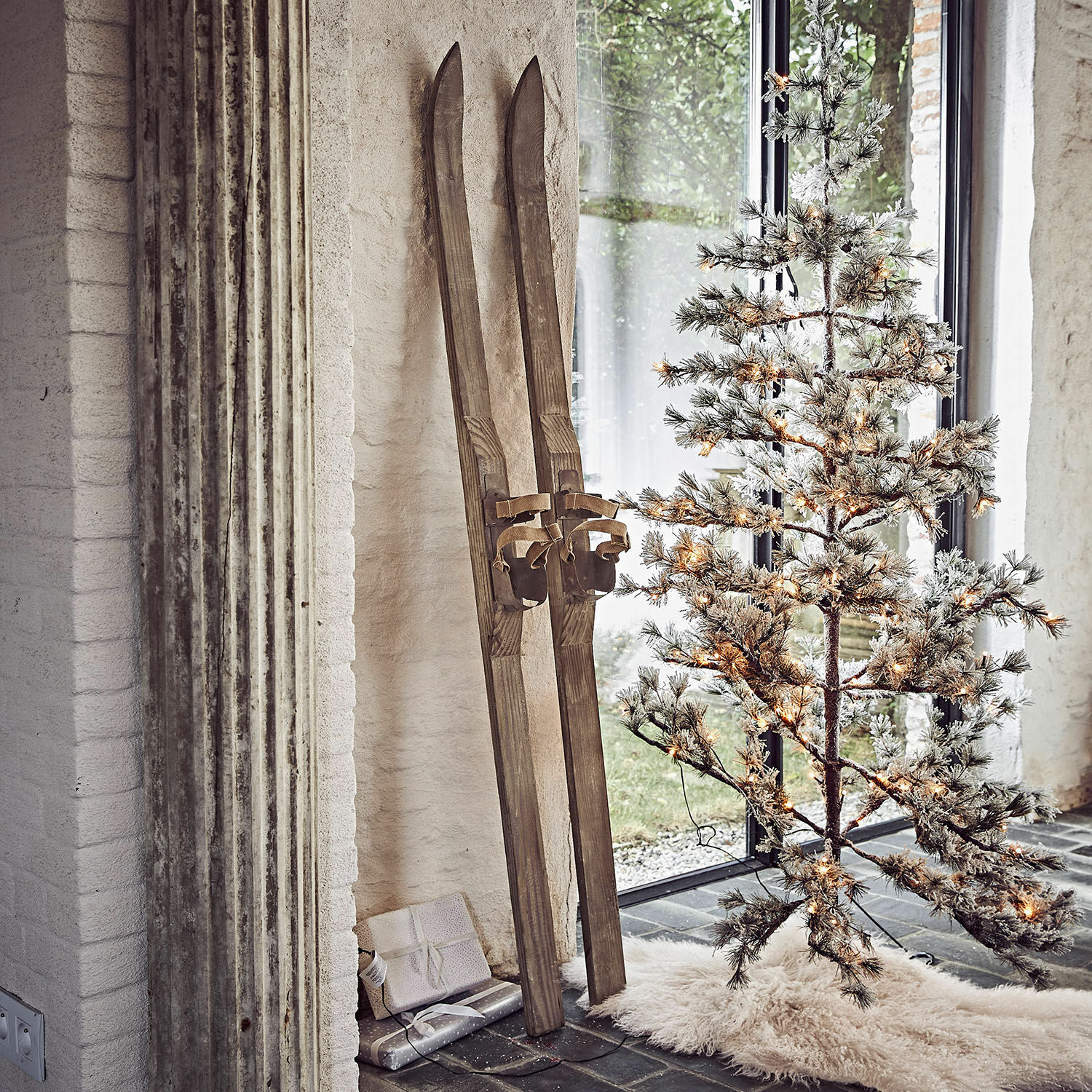 Decoratieve ski set van 2 Lambeth Vintage houten ski's naast verlichte kunstkerstboom op wit vloerkleed