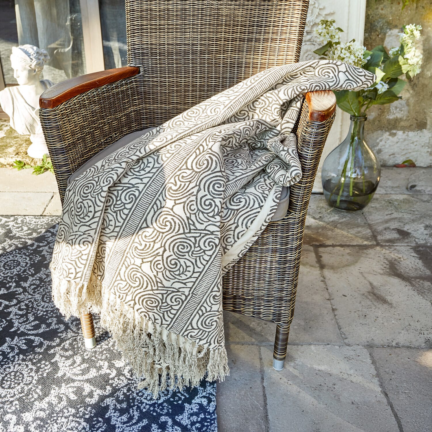 Plaid Ensis Beige deken met patroon en franjes op rotan stoel, woon- en tuindecoratie
