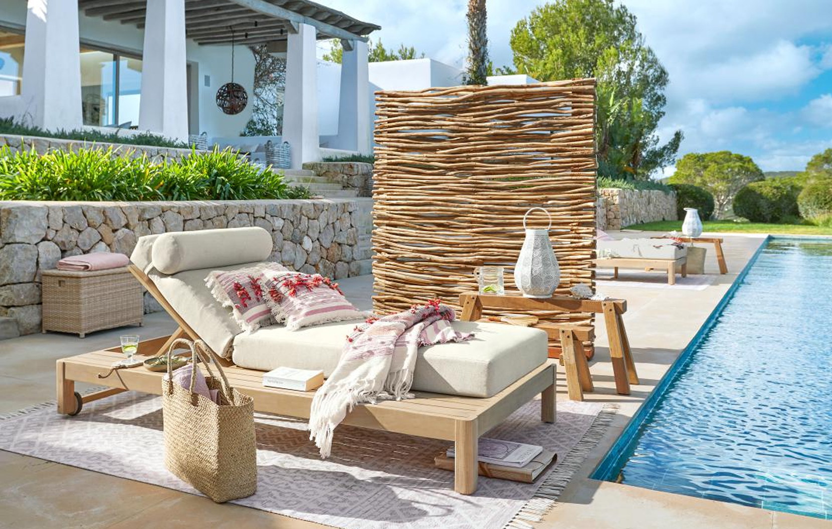 Chaise longue en bois clair avec coussin crème et paravent décoratif au bord de la piscine style marin