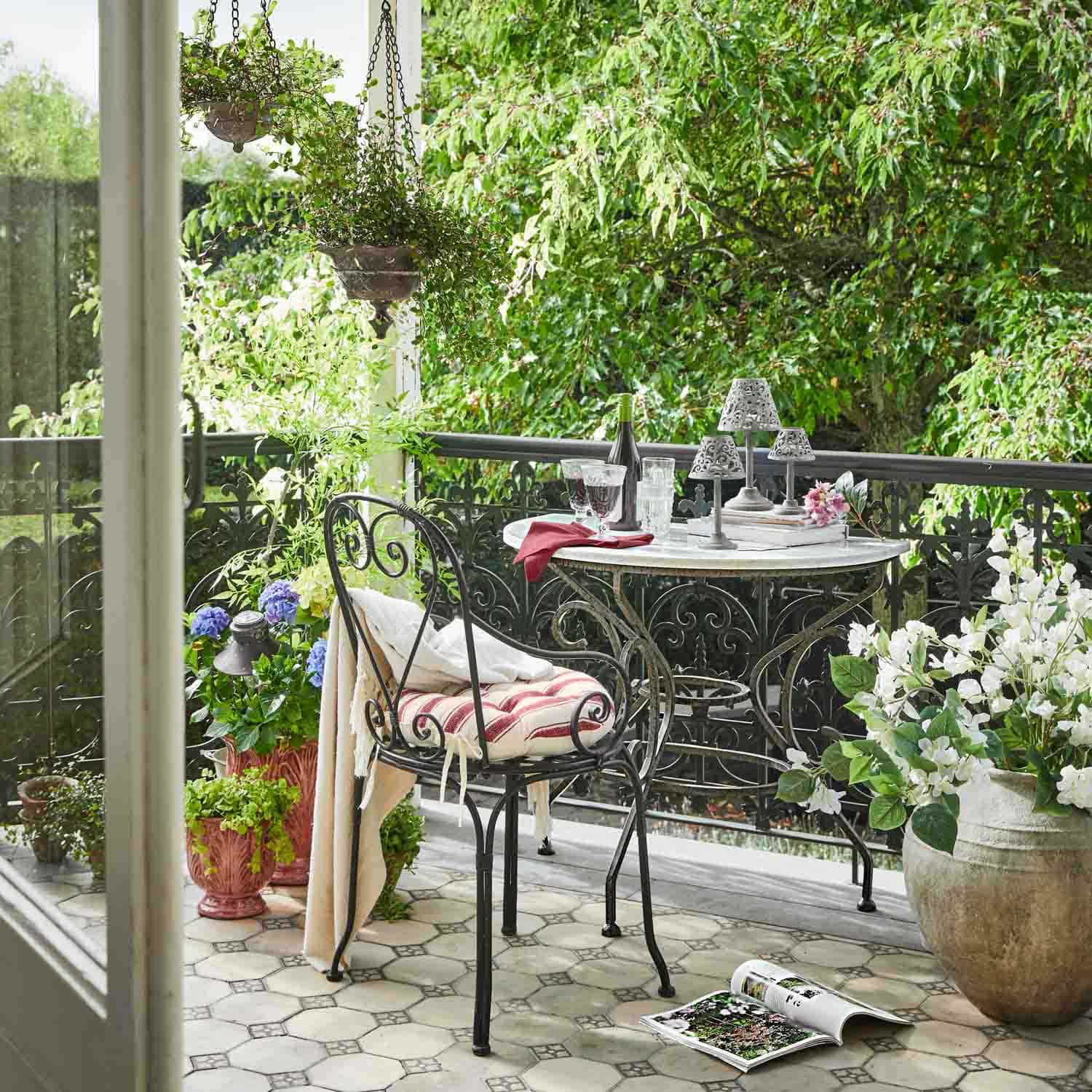 Balcon décoré avec table et chaise en métal, plantes en pots et ambiance relaxante en plein air