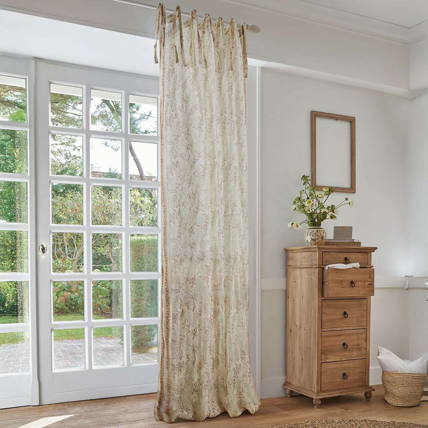 Rideau Floréane Rideau beige à motif floral délicat dans un salon lumineux avec commode en bois et grande fenêtre