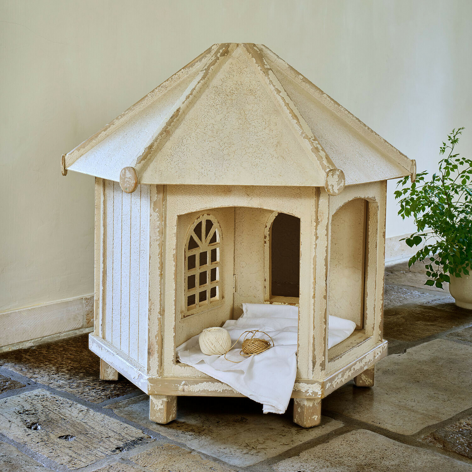 Tuinhuisje voor katten Alvérine Beige houten kattenhuis met ramen en wit kussen op stenen vloer
