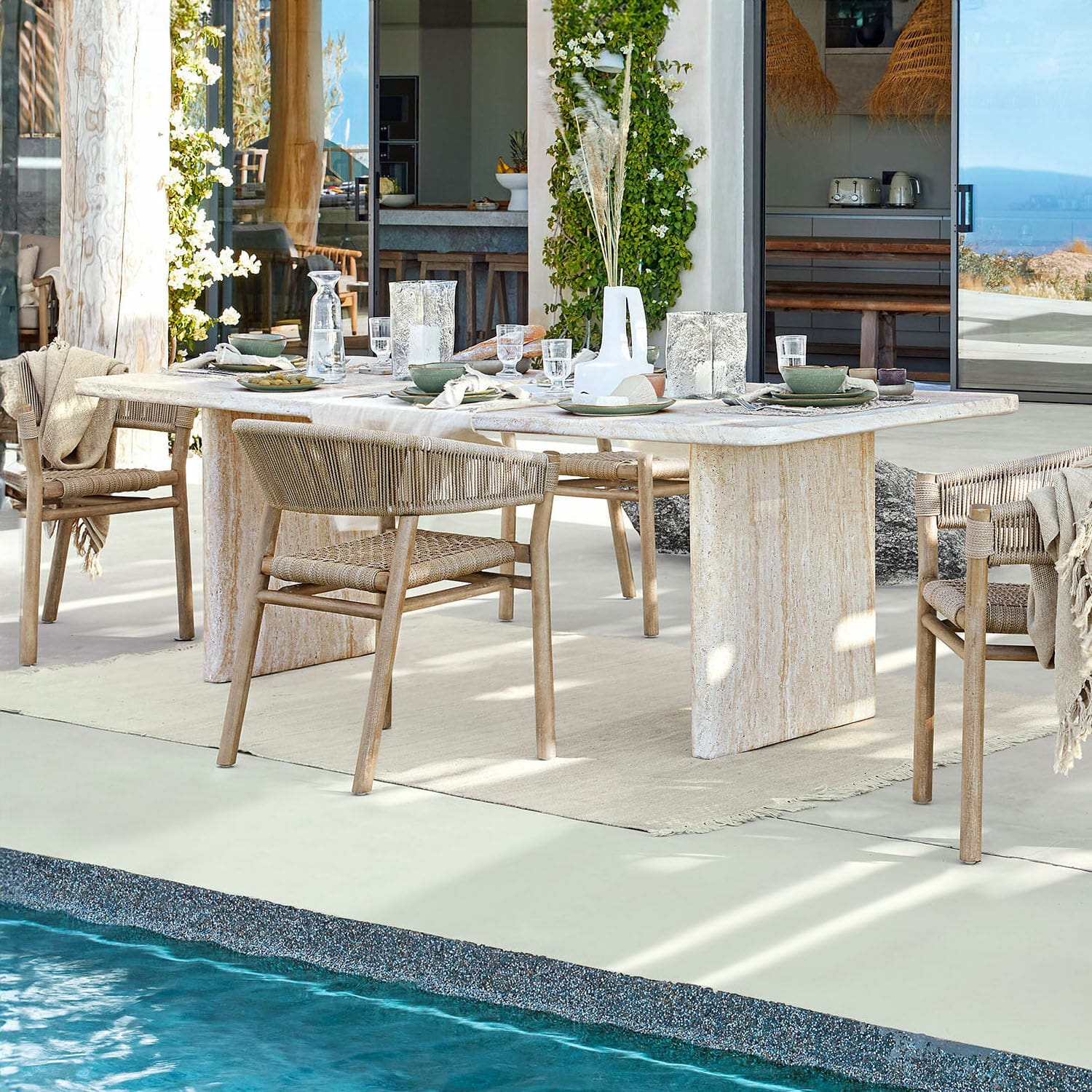 Table de salle à manger Yveline Table à manger en pierre claire avec chaises en bois tressé près d'une piscine dans une maison moderne